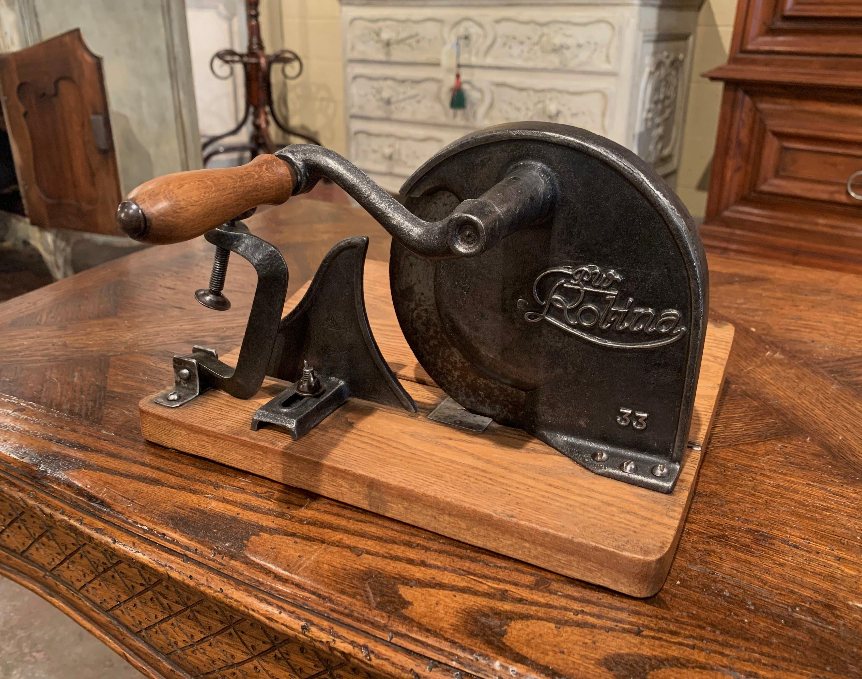 This vintage country slicer was crafted in Germany circa 1920, made of iron and wood, the cutter is mounted on a cutting board, it features an adjustable cutting wheel held with a wooden crank handle and a folding tray. The slicing devise is in