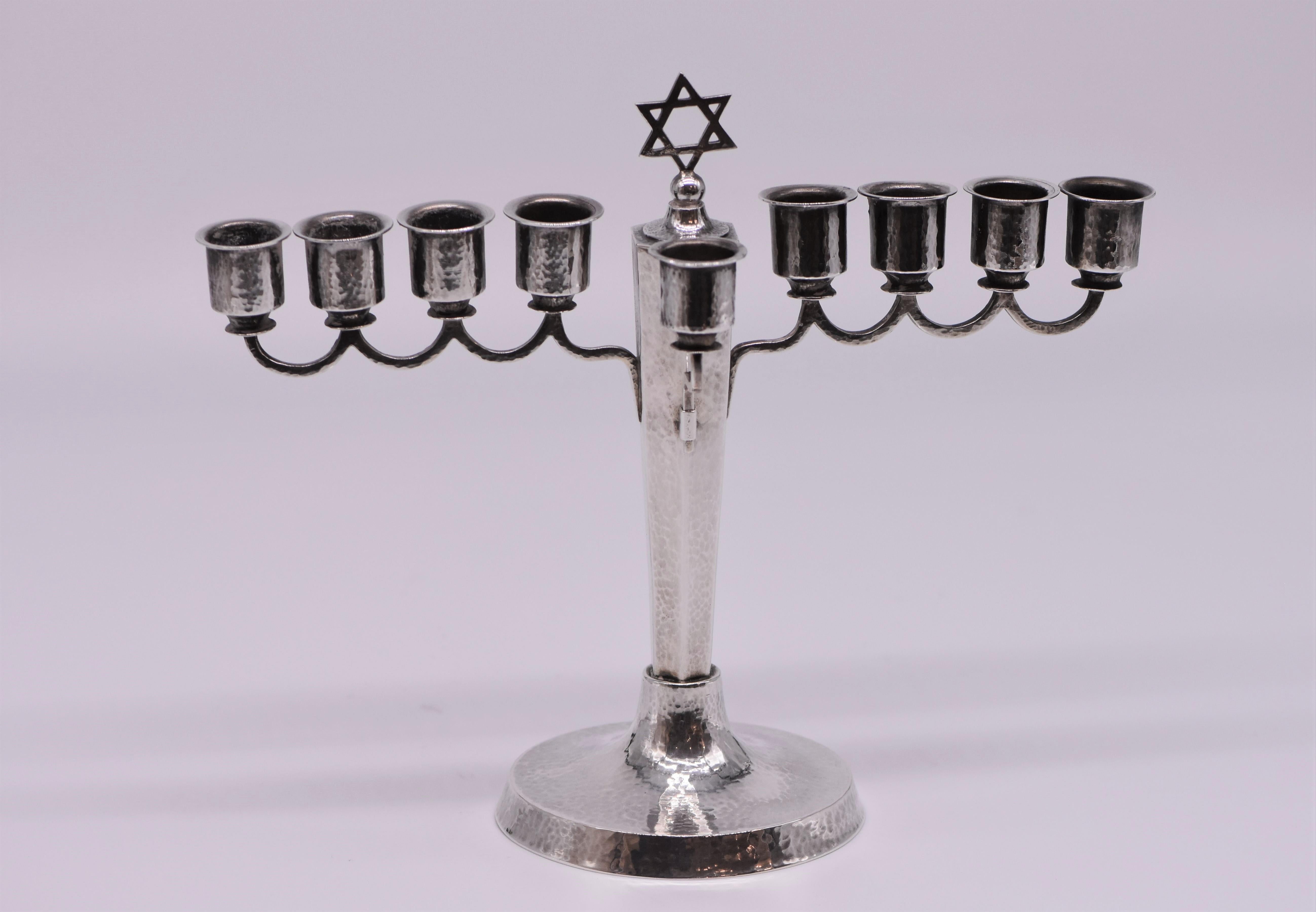 Hand-hammered silver Hanukkah lamp menorah, Germany, circa 1920.
Set on a circular hammered base, the eighth candleholders are set on eight arms.
Topped with a Star of David. Detachable original servant light.
Marked on the base with German