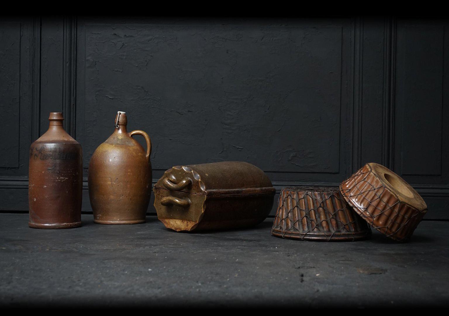 Lovely set of five antique German Earthenware kitchen objects.

You see two large beer bottles or jugs.
Two Gugelhupf moulds (or Kouglof) for baking cake. Both moulds are visibly mended in a very decorative way.
And a real old fashioned Römertopf to