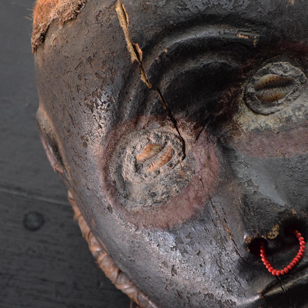 Early 20th century Ghoulish mask 

A highly decorative yet curious object, of African origins unknown, this hand-crafted mask is for display and decorative purposes only. Decorated with many beads, stones, coconut husk for hair and what resembles