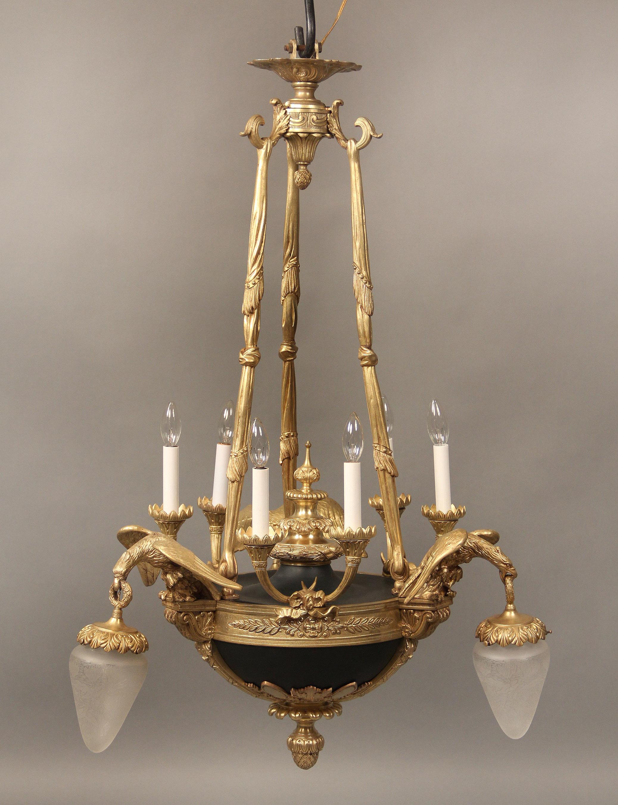 An Interesting early 20th century gilt and patinated bronze nine-light Empire style chandelier.

Three curtain designed ropes run from the top to the body, centred by a large urn, six torch arms with lights and three eagles with spread wings and