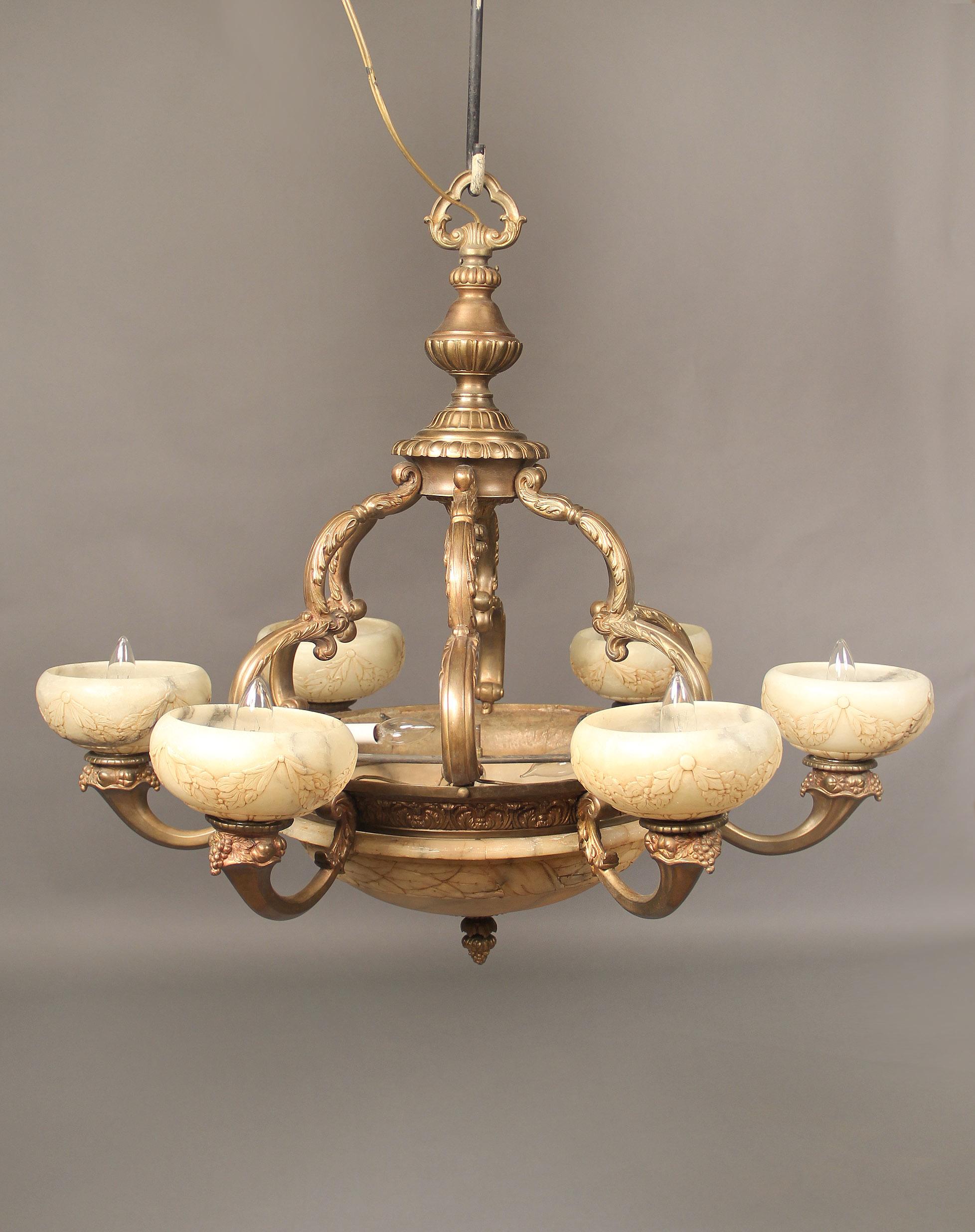 An early 20th century gilt bronze and carved alabaster nine-light chandelier

Gilt bronze frame with six arms connecting the top with the body, the base with a large carved alabaster bowl, six bronze arms designed with fruit and carved alabaster