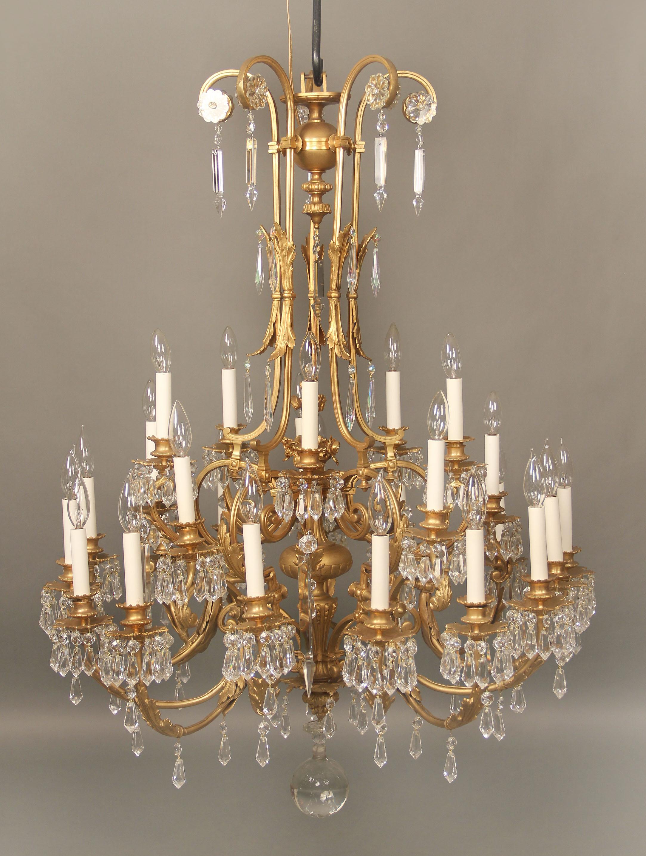 A fine early 20th century gilt bronze and drop crystal twenty-five-light chandelier

Numerous shaped drop crystal along the arms and cups, bronze floral central design, twenty five tiered perimeter lights.