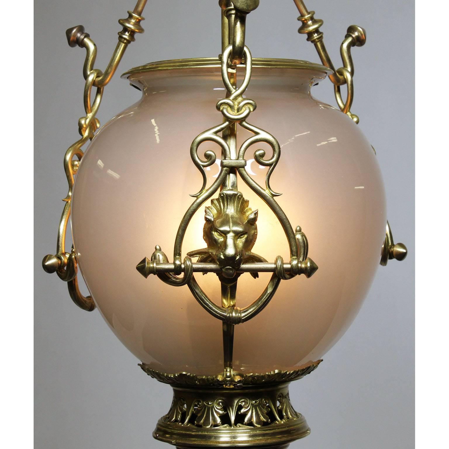 Un raro pendente a lanterna continentale in stile neoclassico Revival in bronzo dorato e vetro opalino. Il globo ovoidale in vetro soffiato smerigliato, con tre luci interne, è sospeso da tre ganci ornamentali centrati da leoni, la parte inferiore
