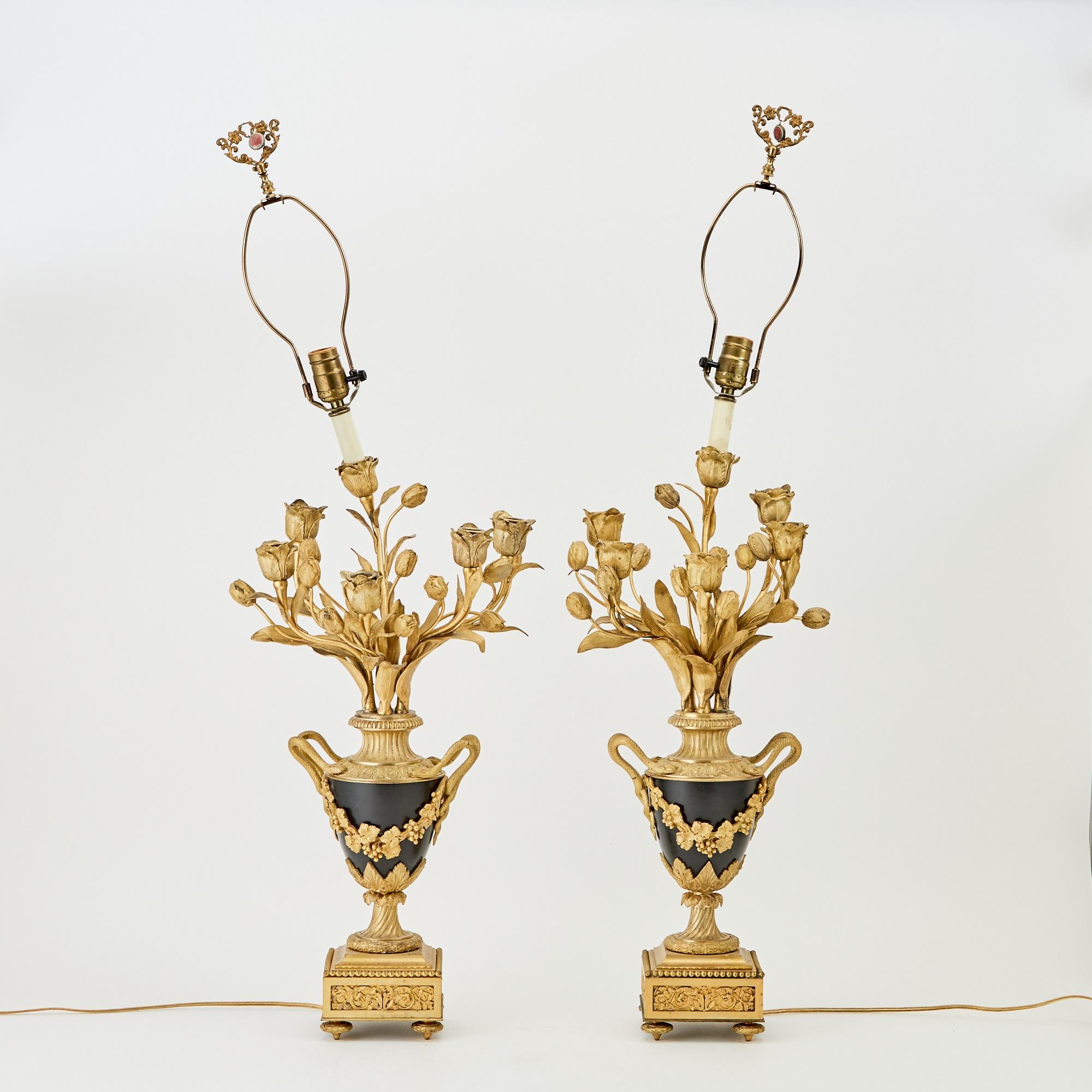Esta exquisita lámpara candelabro de cinco brazos, fabricada a principios del siglo XX, encarna el opulento estilo Luis XVI. Adornada con suntuosas monturas de bronce dorado, la lámpara presenta candelabros florales y foliados, que desprenden una