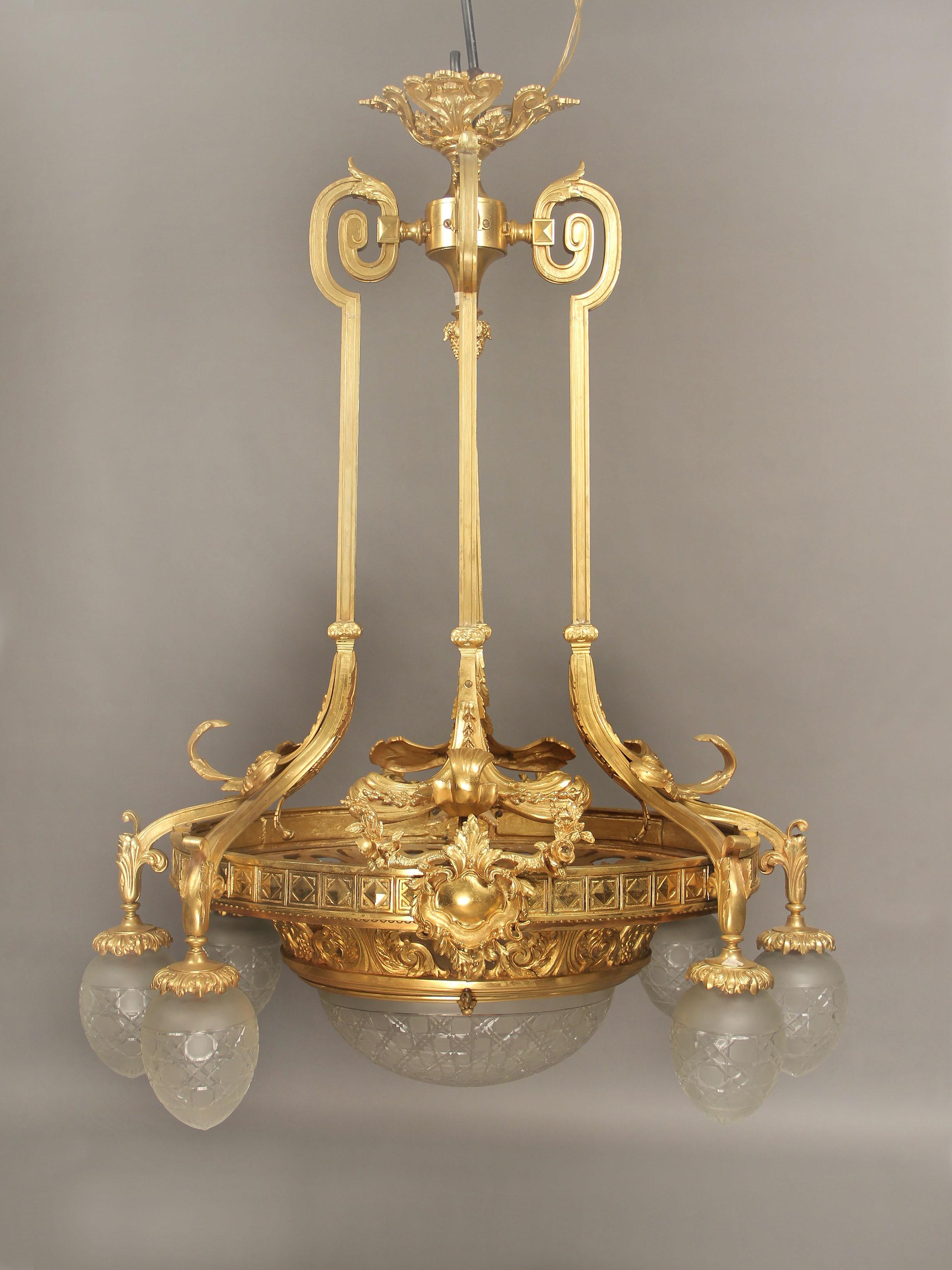 A wonderful early 20th century gilt bronze ten-light chandelier.

A long and oval bronze frame with casted scrolled arms extending to six perimeter lights with fine cut French crystal shades, the bottom centered with foliate designs and a matching