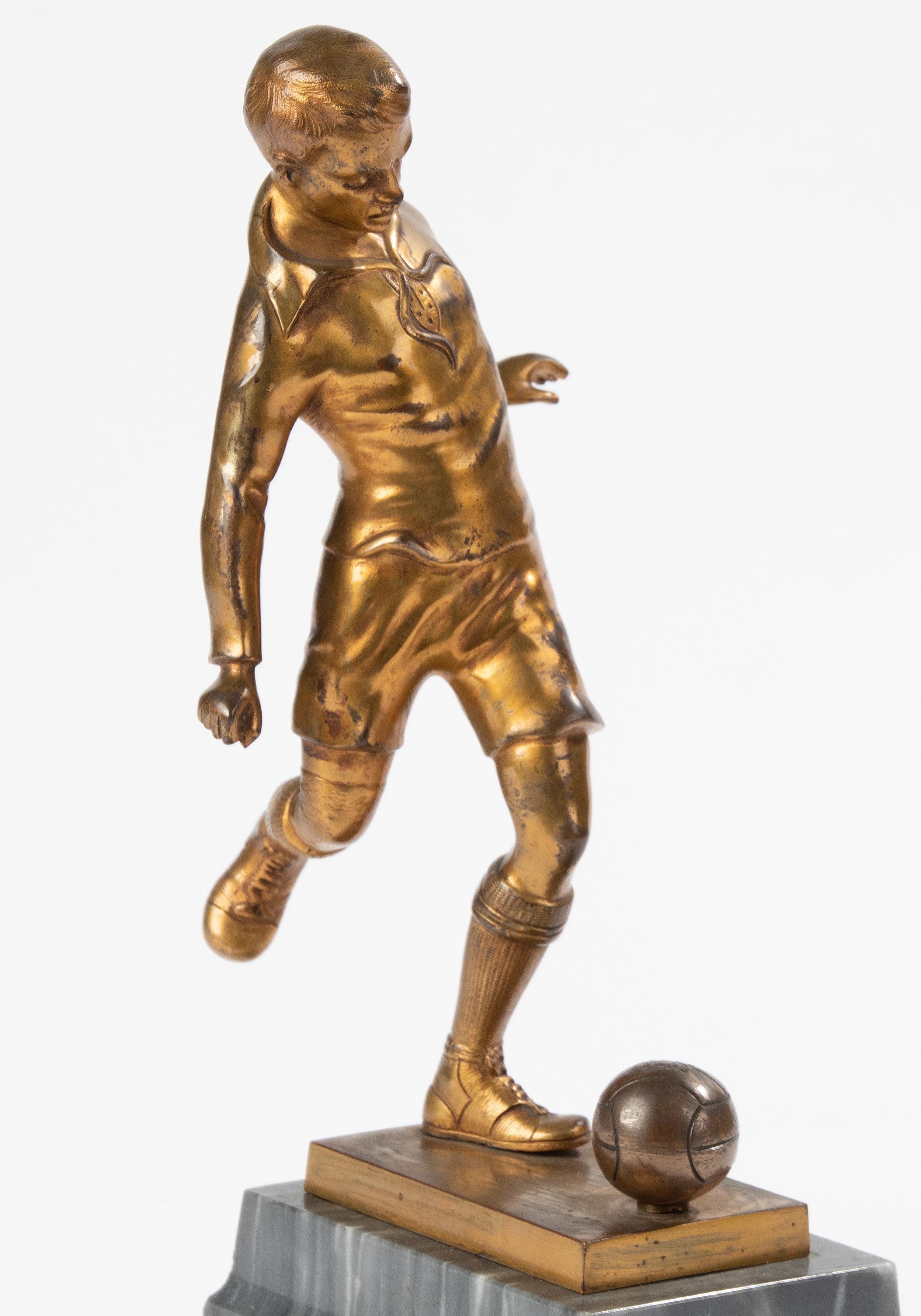 An Art Deco period sculpture of a football / soccer player. The sculpture is made of spelter (zinc alloy), with the original gilt patina. Resting on a 
