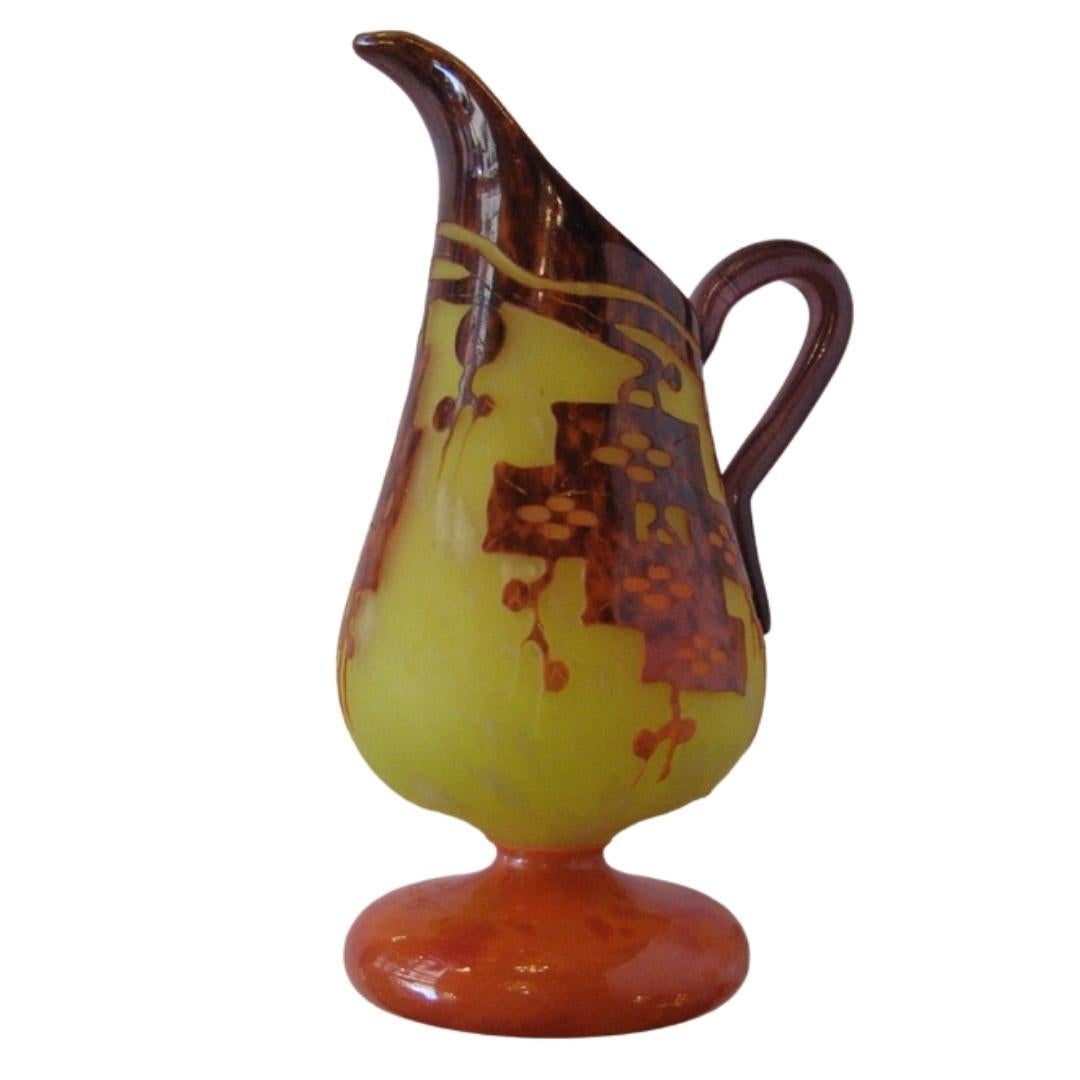 Glass ewer
Overlaid and acid-etched with stylized motifs mottled tortoise maroon on vibrant yellow
Coral base and eggplant handle.
Signed Le Verre Francais on the base, circa 1925

Le Verre Francais is one of the many types of cameo glass