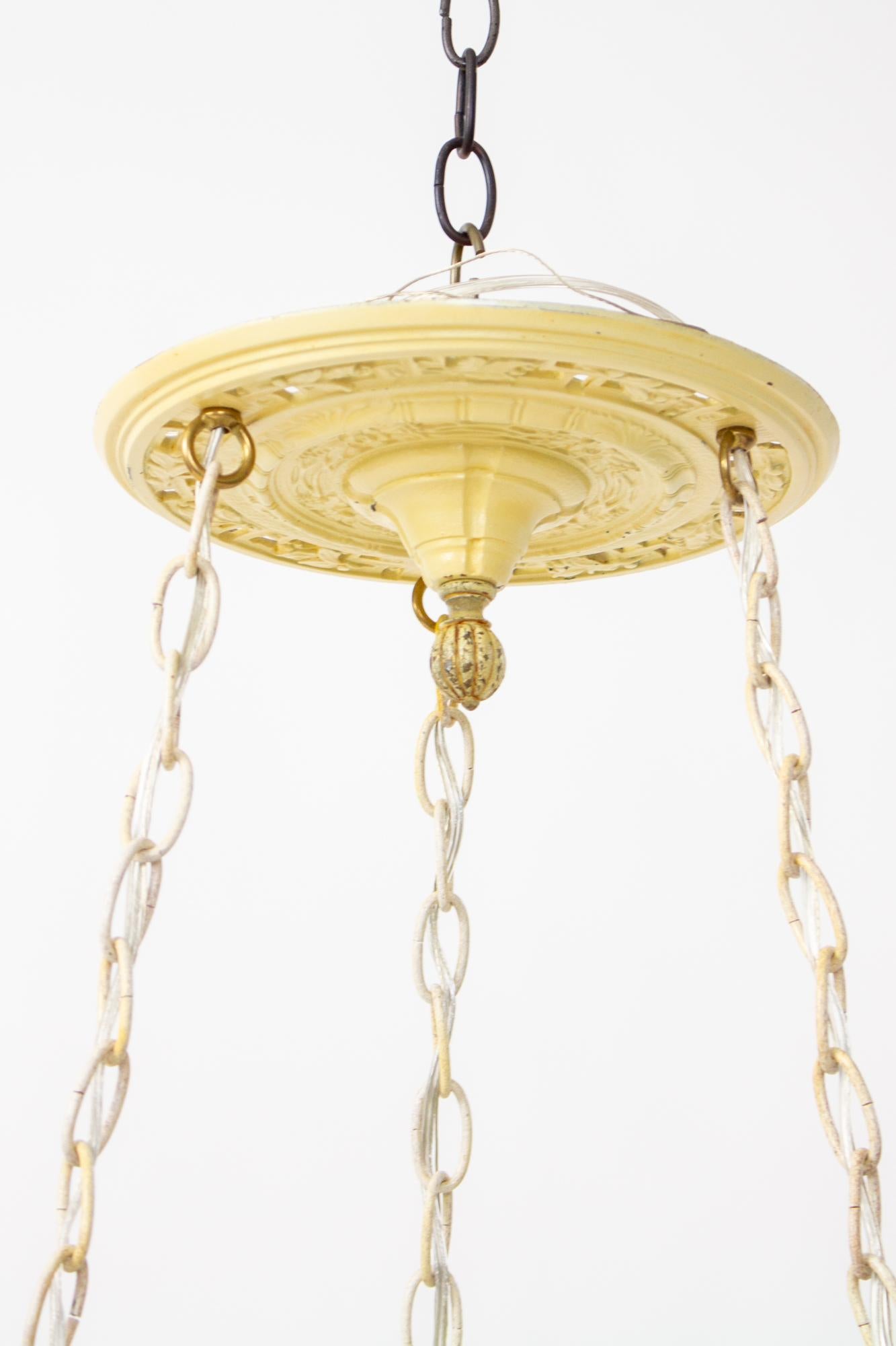 Early 20th Century glass flower bowl fixture. A frosted glass bowl fixture with reverse painted yellow flowers. The bowl is lit by three lights and hangs from three chains. The chain and canopy are ivory with the original painted finish. The canopy