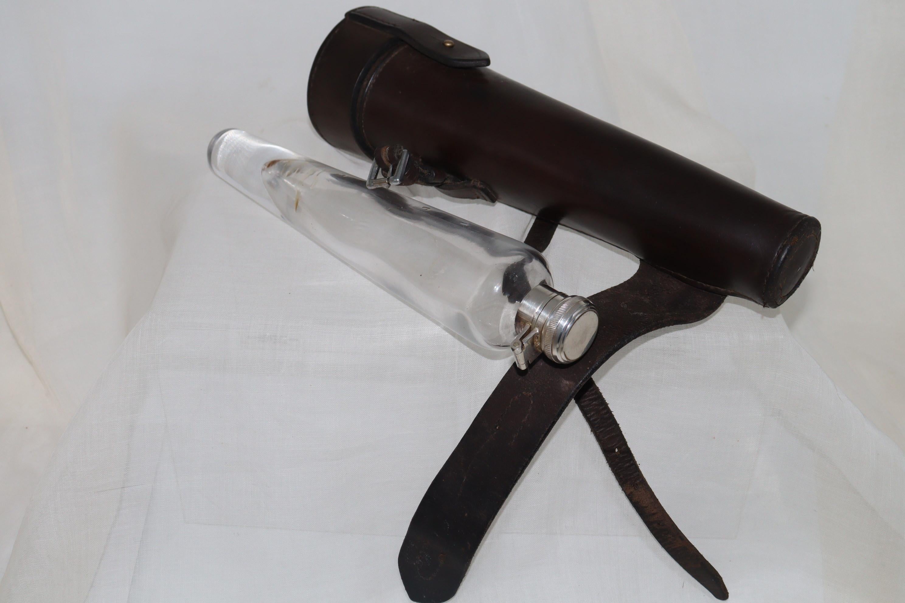 This heavy glass hunting flask is housed in its nicely made leather case, ready to strap to the saddle. To hold the contents, the flask is fitted with a silver plated lid secured with a twisting action to release the bayonet fitting. The leather