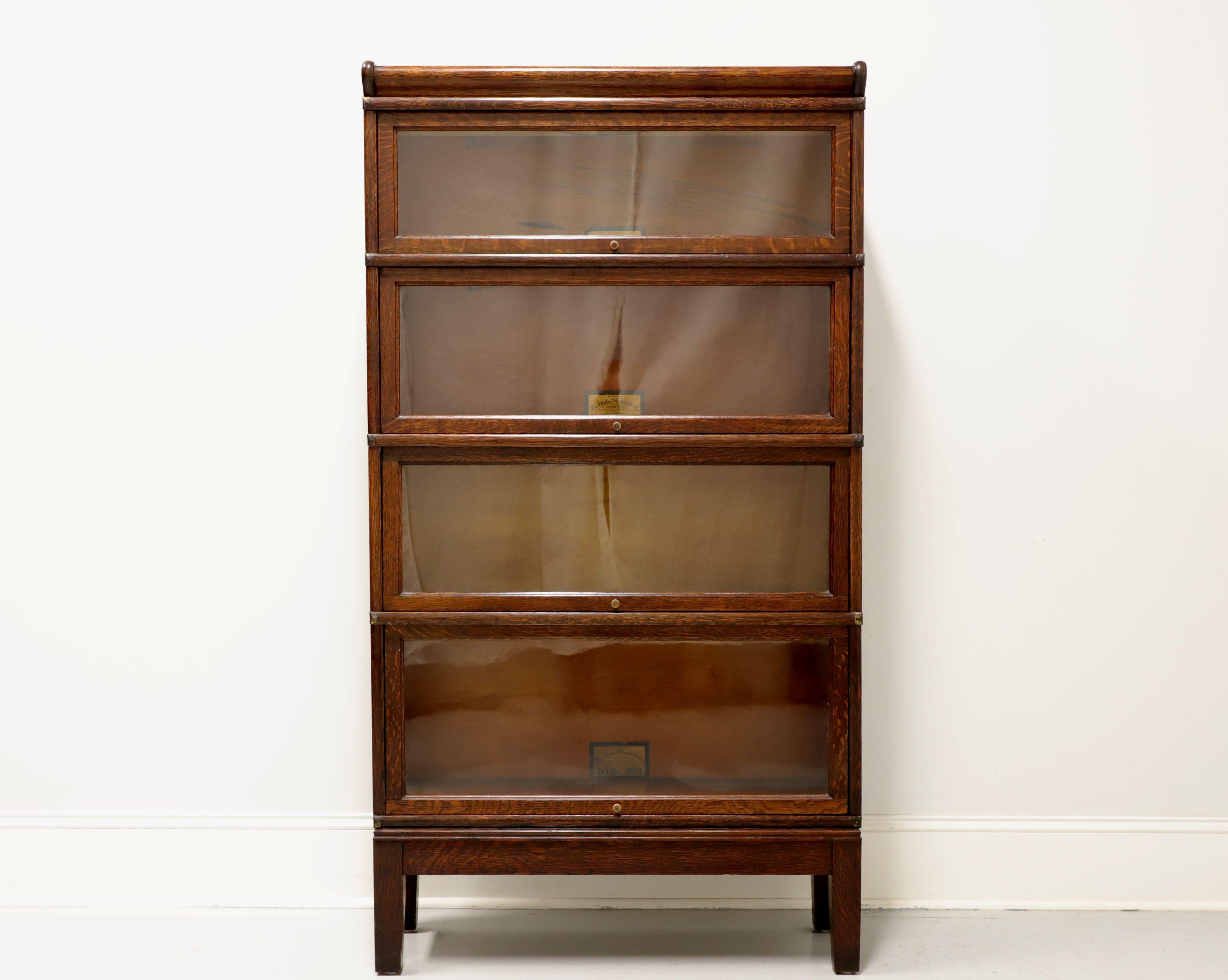 An antique Arts & Crafts style stacking barrister bookcase by Globe Wernicke of Cincinnati, Ohio, USA. Quartersawn tiger oak with brass knobs and brass side accents/supports. Features crown, four various size stacking flip up slide back glass door