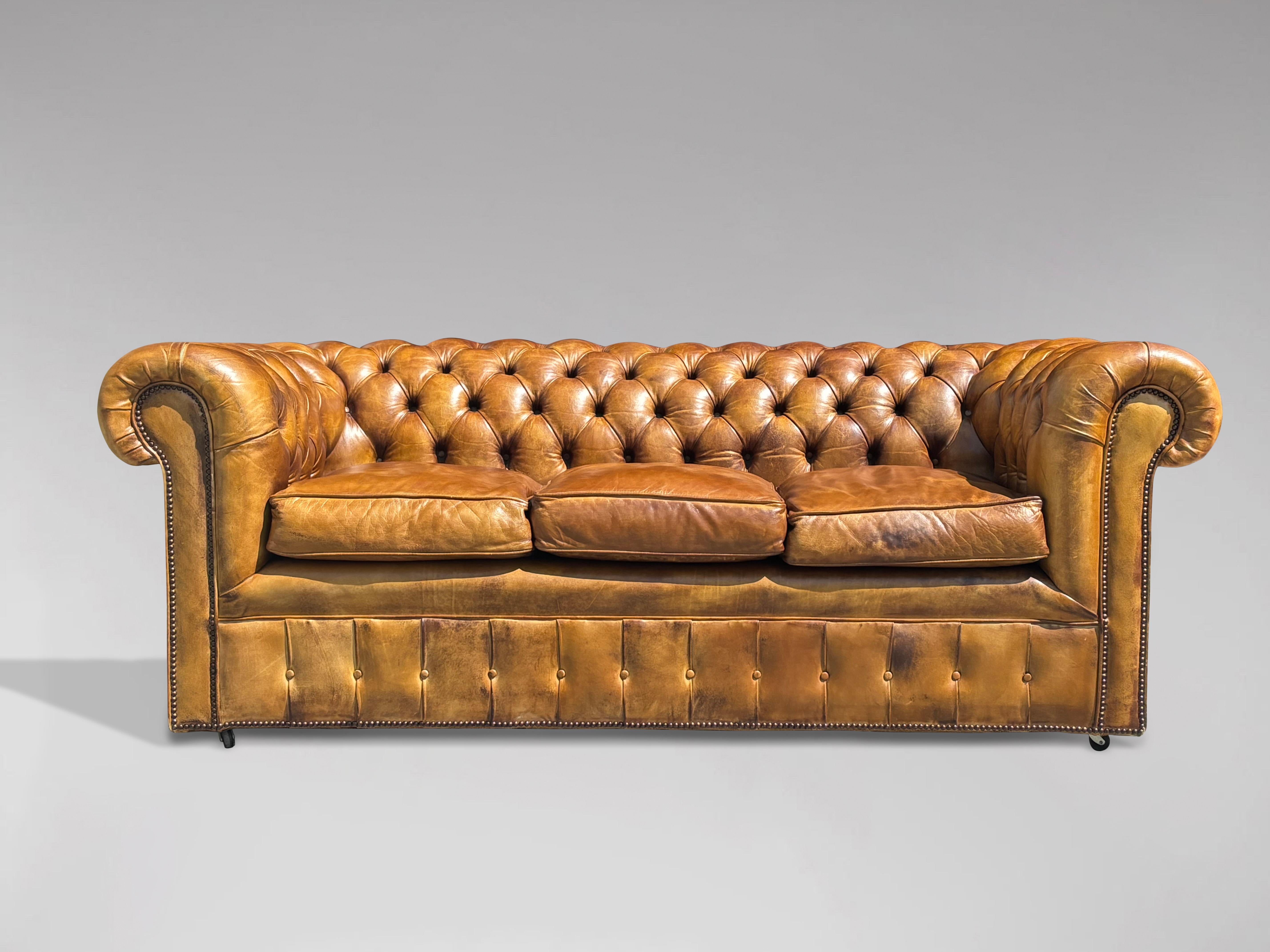 Chesterfield à trois places en cuir brun doré, de qualité exceptionnelle, datant du début du 20e siècle, avec trois coussins en plumes détachés, monté sur roulettes. Avec garniture en laiton cloutée individuellement à la main. Un bel exemple de