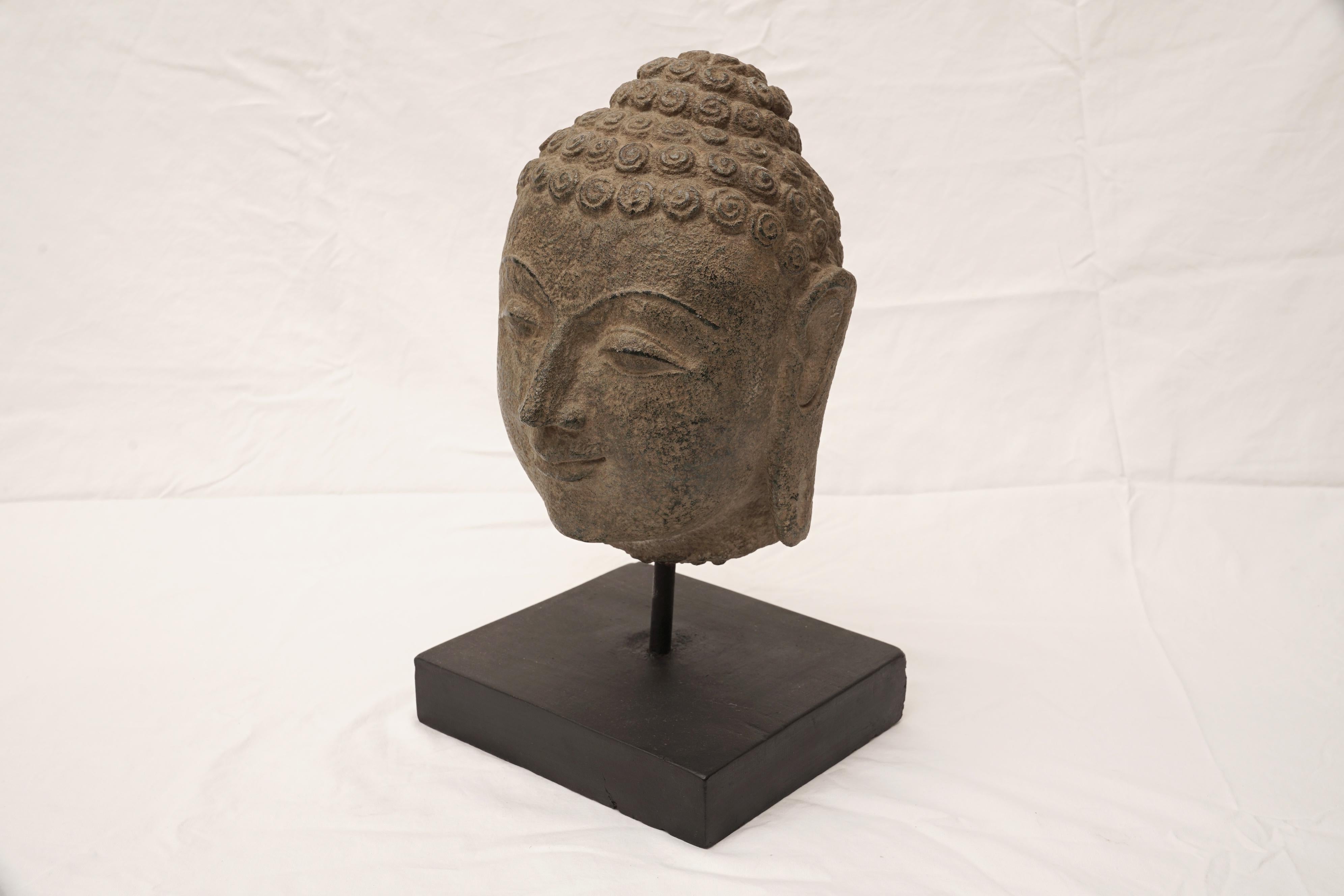 A beautiful Buddha head made of granite dating from the early 20th century. Features include the typical curled hair, elongated ears and half-closed eyes. The Ushnisha crown depicts the wisdom and illumination after attaining enlightenment. In