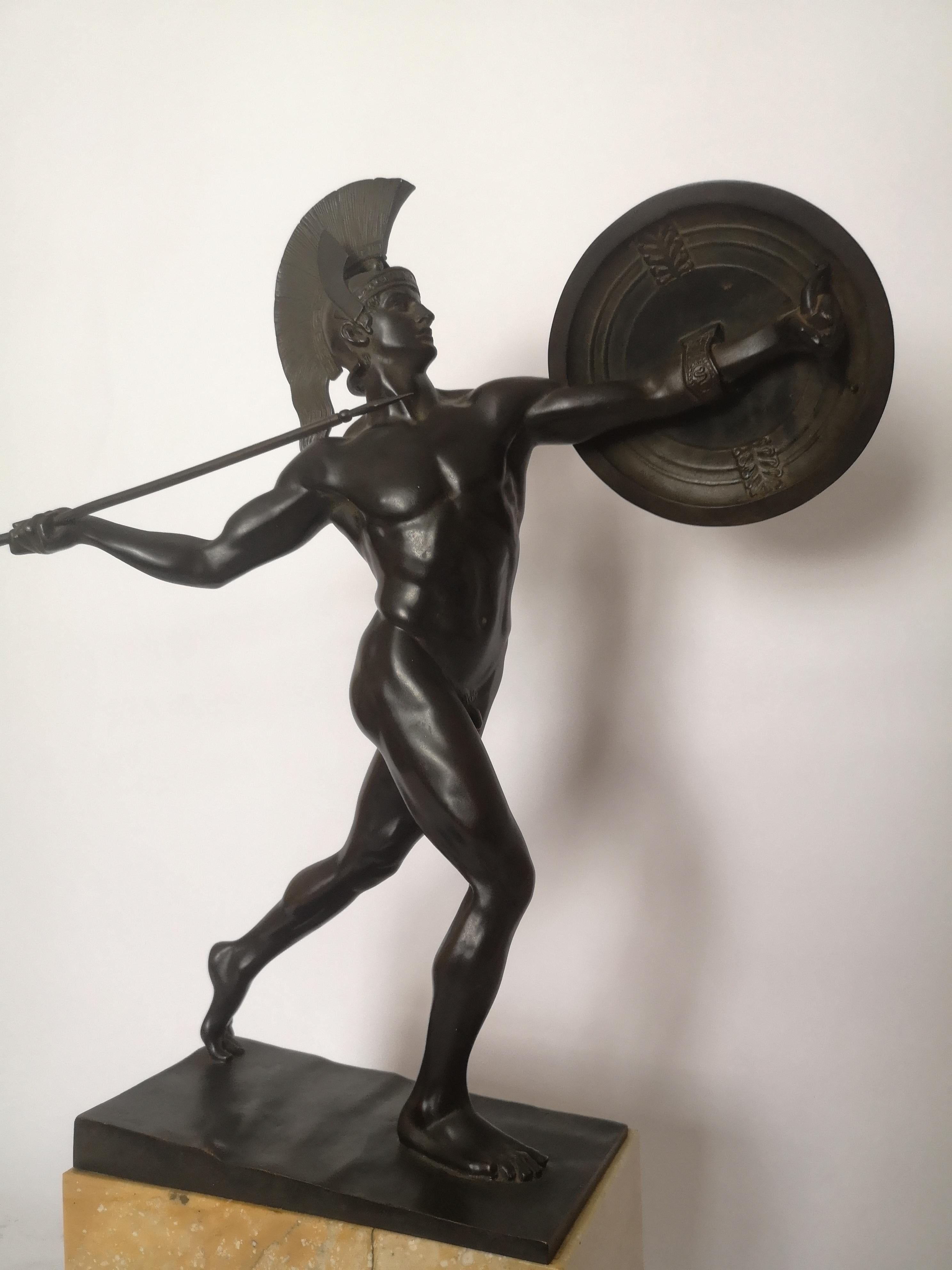 This bronze depiction of Greek mythology figure Achilles, hero of the Trojan war. Shown here in bronze in an action position with spear poised in his right hand and his shield, bearing a central bull decoration, on his left arm. His helmet imitating