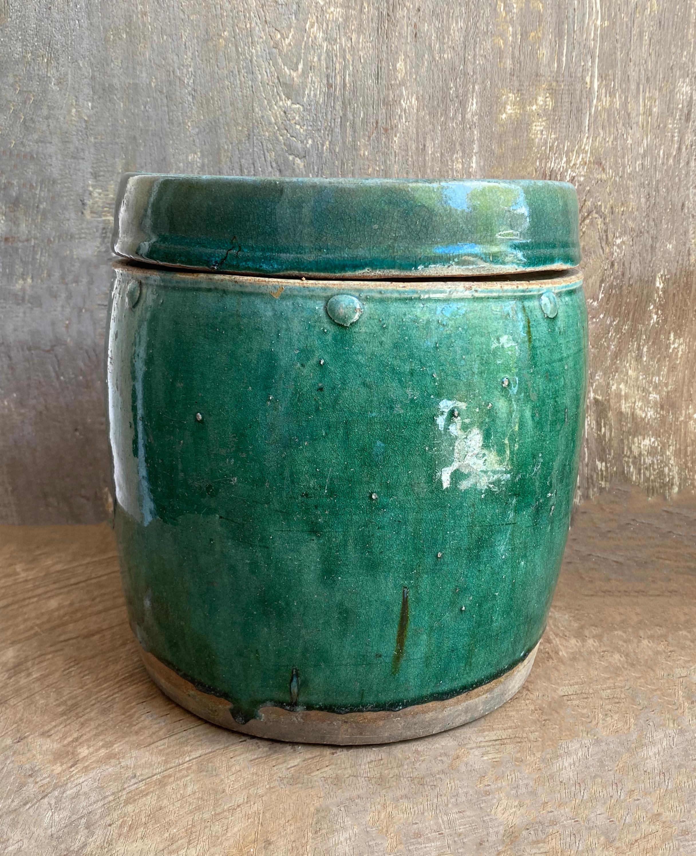 This jar from early 20th century China was used to store and transport medicinal herbs and spices. This barrel-like shape with a flat lid made it suitable for stacking. Despite its original utilitarian function the jar features a beautiful green