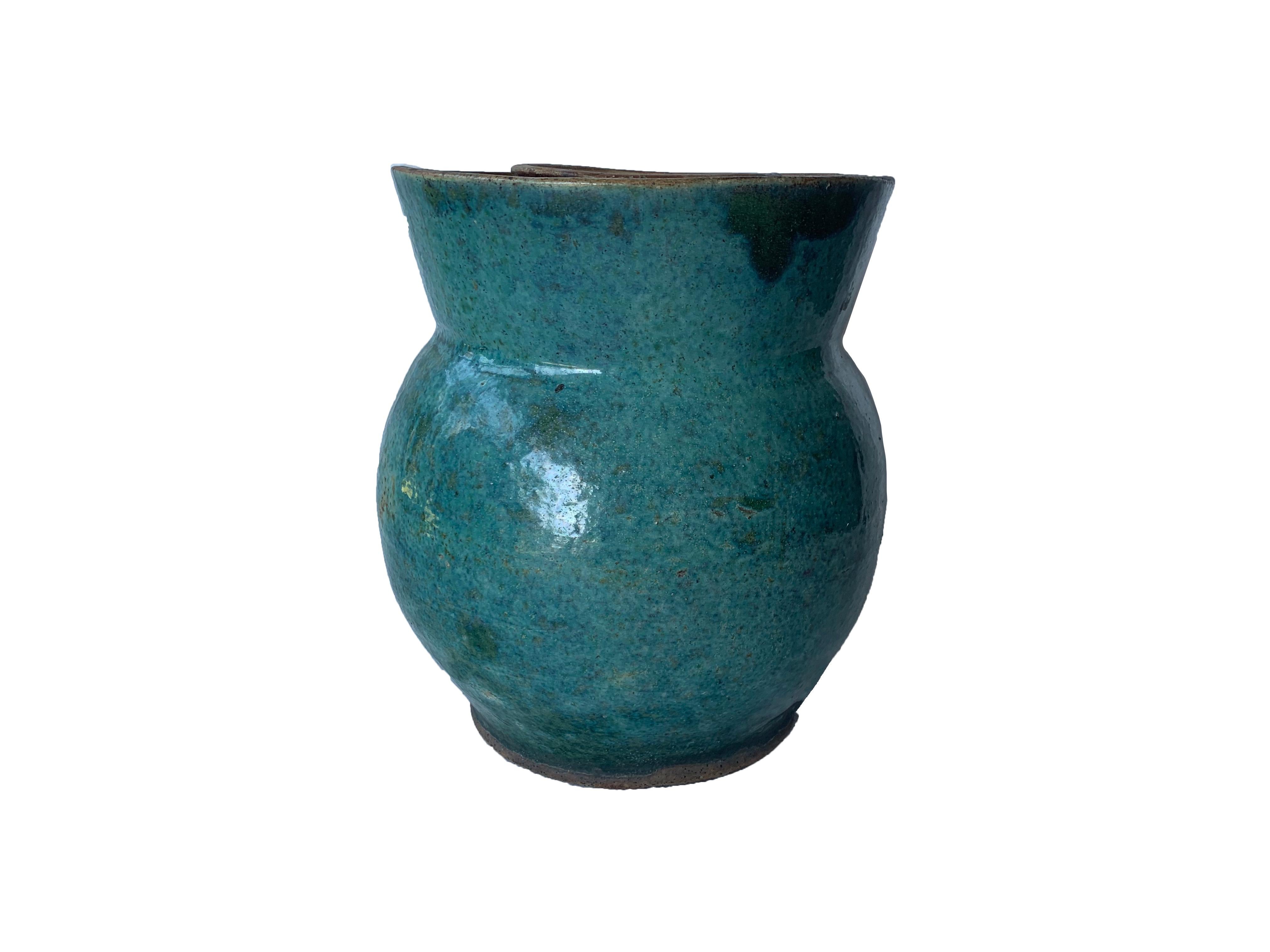 This early 20th century Shiwan fermentation jar features a sunken rim where water would have been filled (forming a barrier) to prevent insects and other pests from climbing into the jar's opening and eating its contents. It features a green-glaze