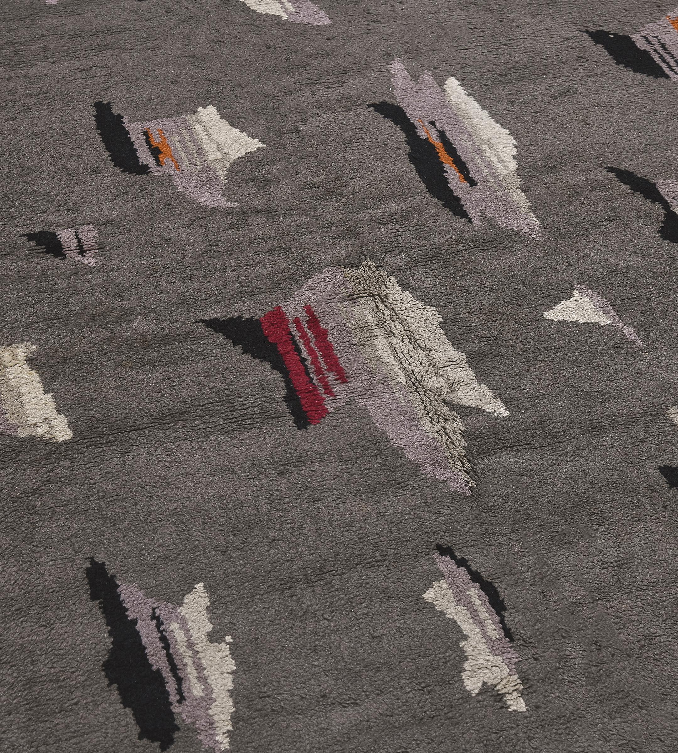 Esta alfombra tradicional deco francesa tejida a mano tiene un campo general gris mate de geometría deco matizada que sugiere una caprichosa bandada de pájaros de pecho rosa en vuelo.
