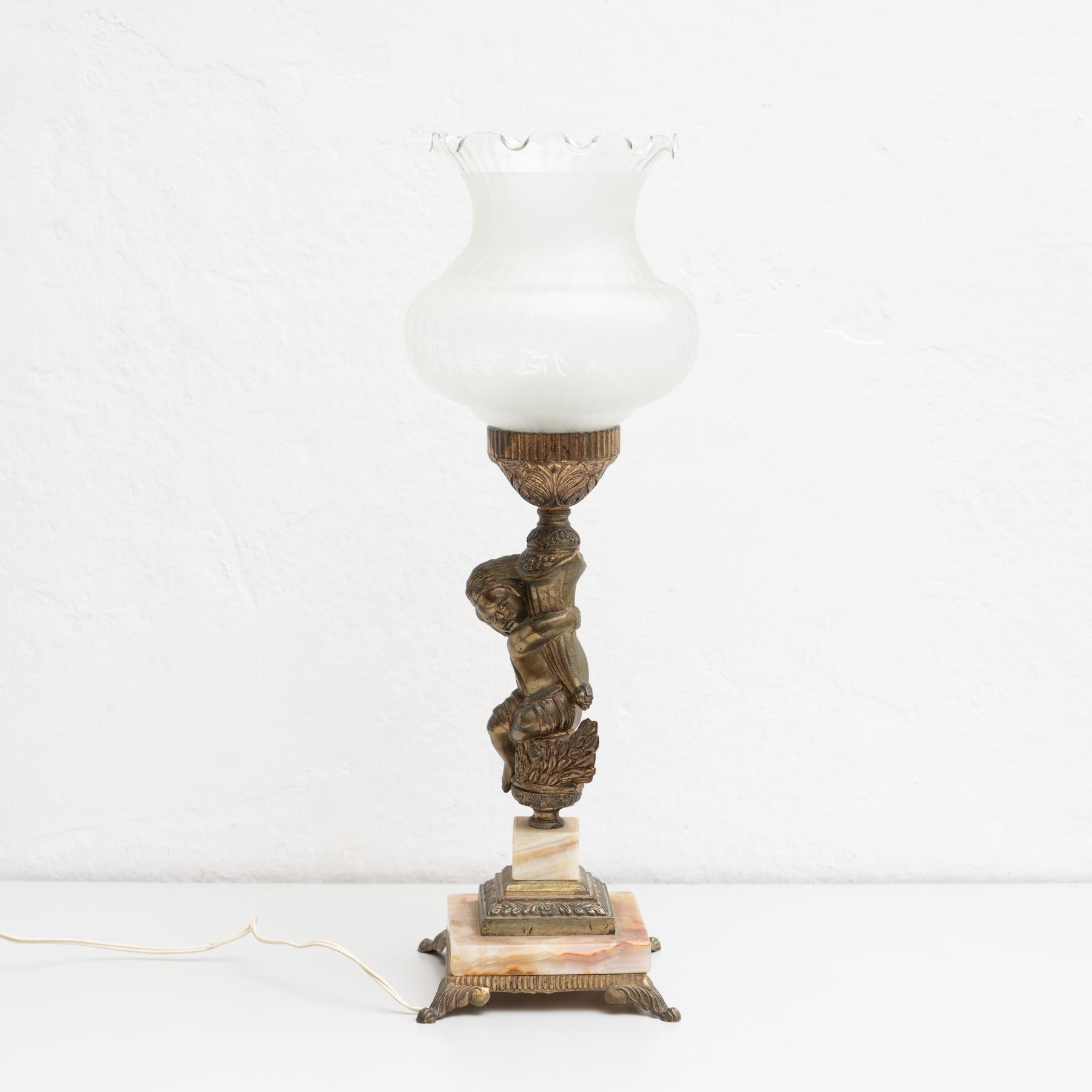 Early 20th century table lamp, with a beautiful decoration of a hugging child.

Manufactured by unknown designer in Spain.

In original condition, with minor wear consistent with age and use, preserving a beautiful