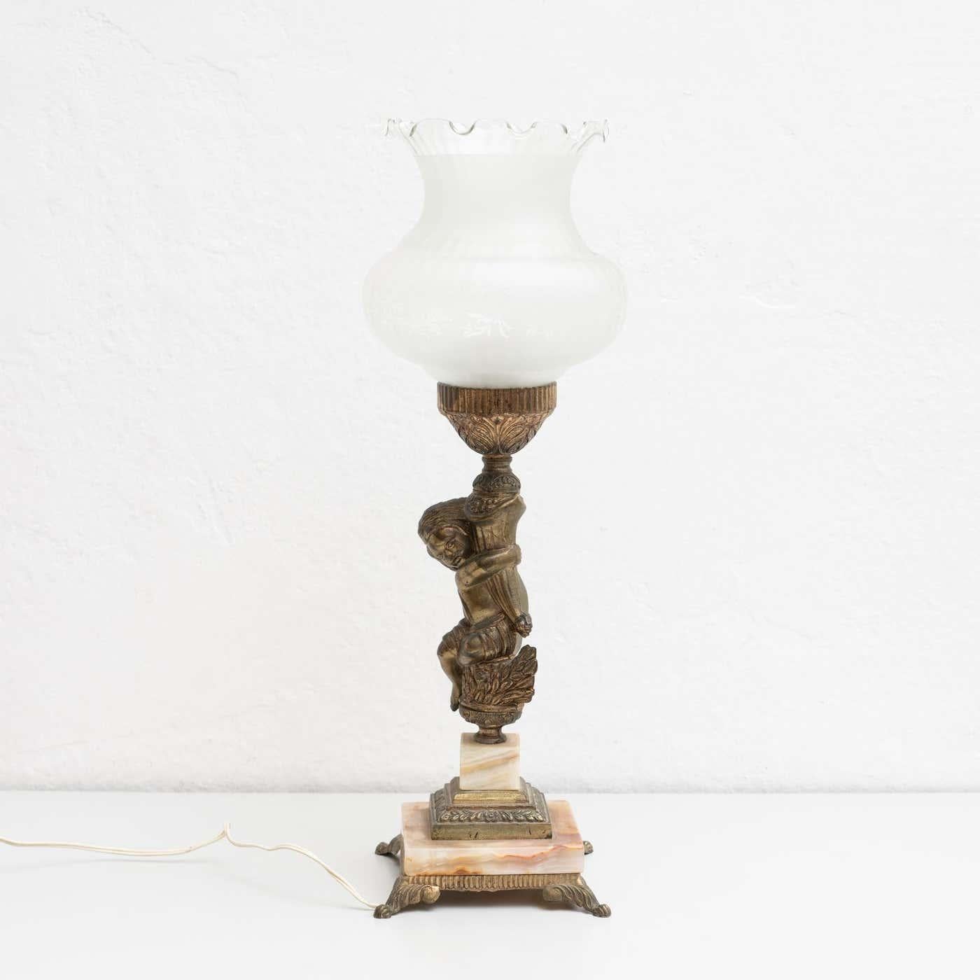 Lámpara de sobremesa de principios del siglo XX, con una bella decoración de un niño abrazado.

Fabricado por un diseñador desconocido en España.

En su estado original, con pequeños desgastes propios de la edad y el uso, conserva una hermosa