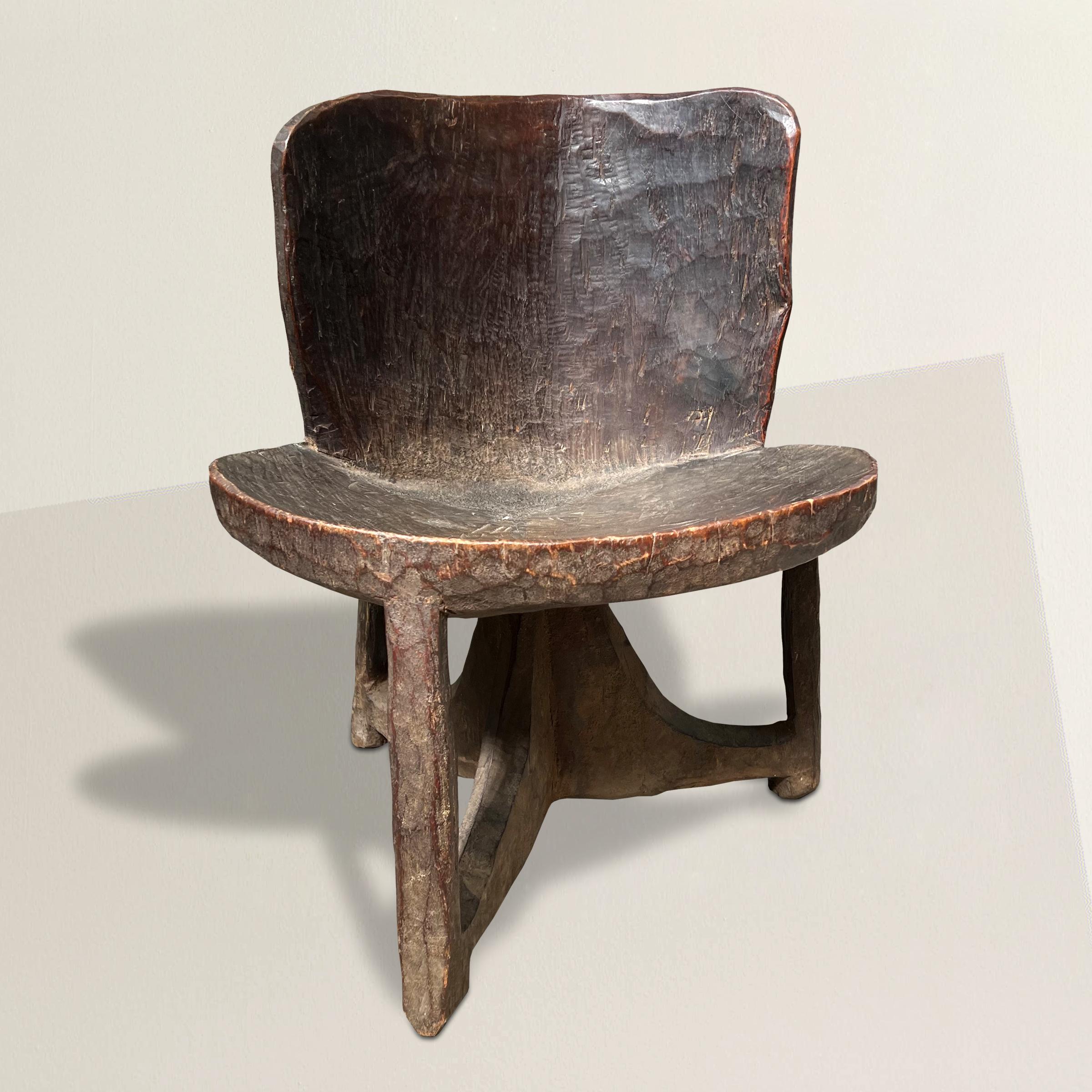 Une étonnante et rare chaise Gurage Peoples éthiopienne du début du 20e siècle à l'esprit moderniste, sculptée d'une seule pièce de bois avec un dossier incurvé et une assise ronde et convexe soutenue par trois pieds, et avec une incroyable patine