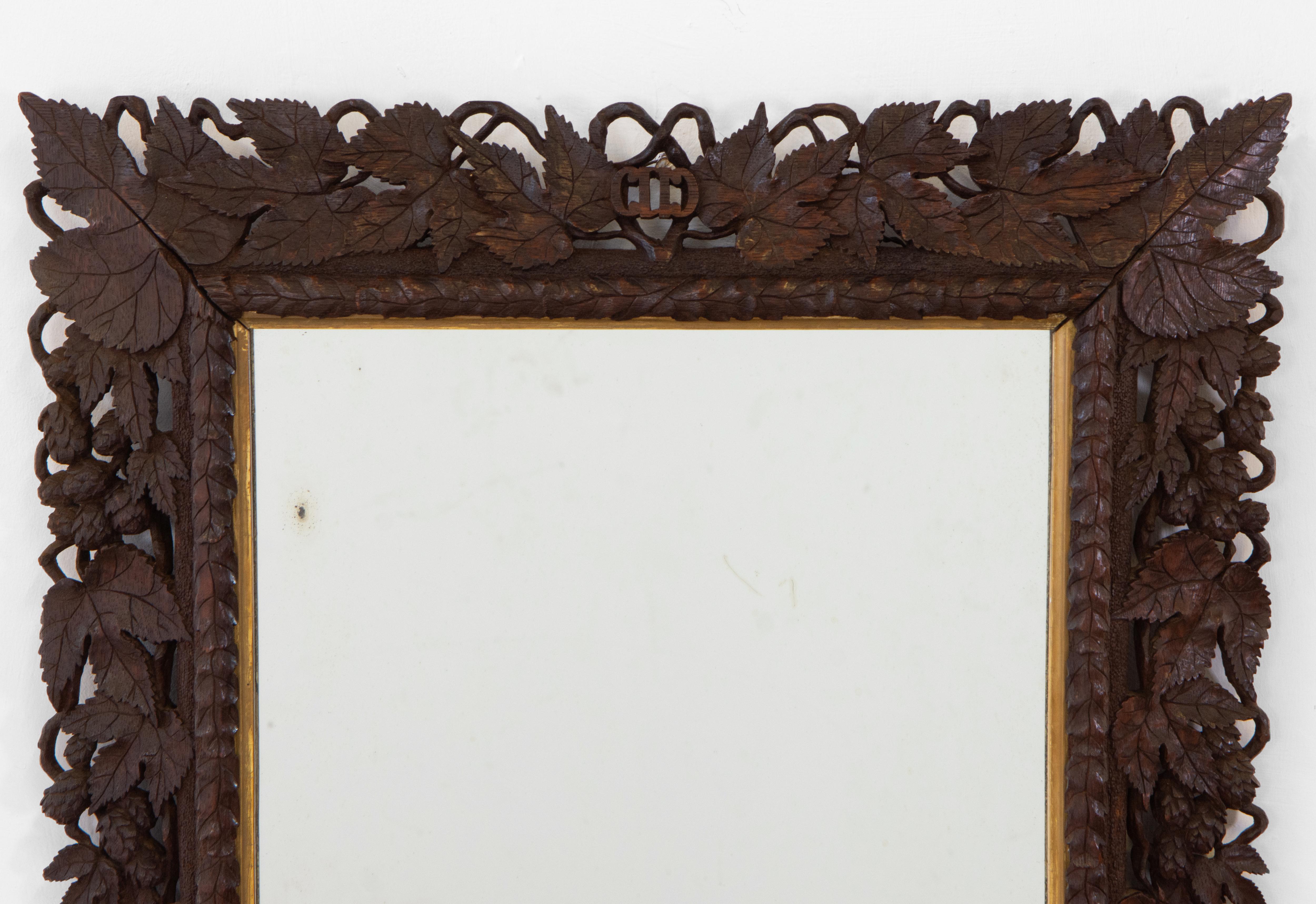 Early 20th century beautifully detailed hand-carved oak Black Forest wall mirror, adorned with grapevines and leaves, and with a gilt wood inset. Circa 1910.

The mirror plate appears to be original, and has some blemishes with age. Pine beading has
