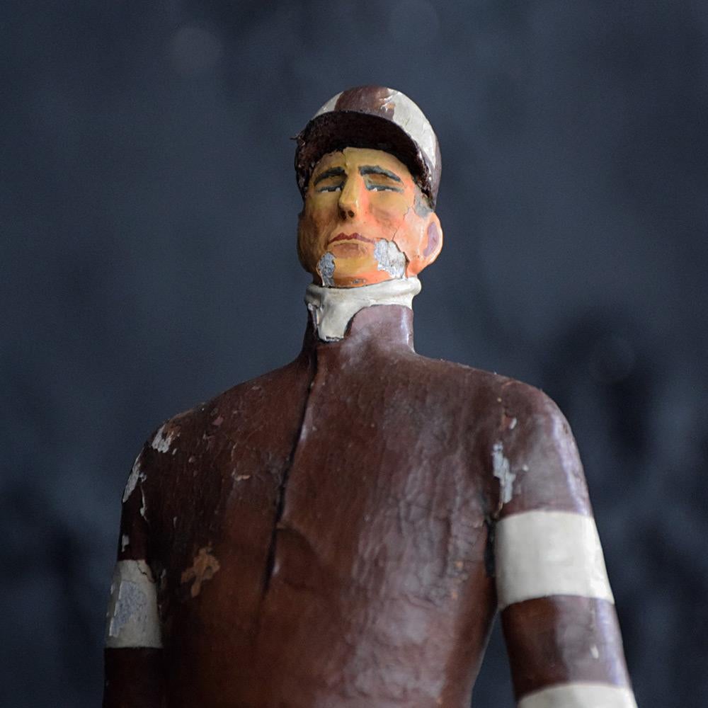 Early 20th century hand carved papier mache jockey figure

An unusual English folk-art early 20th century papier mache figure, of a winning jockey. Standing proud with chest puffed out and whip in hand. This figure stands firmly on a textured fake