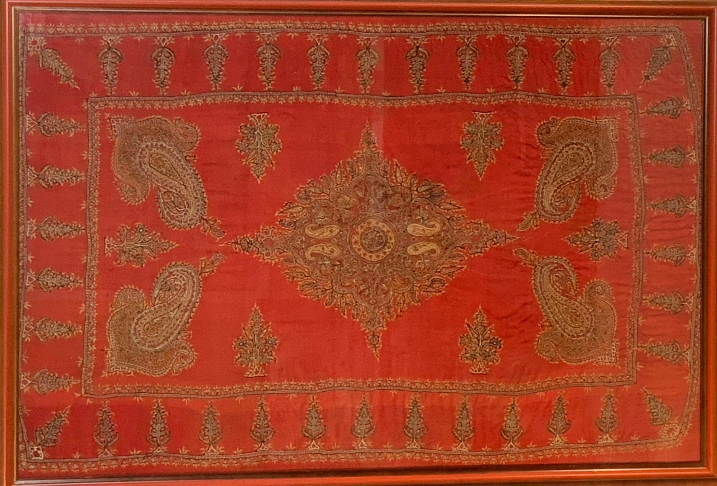 An exceptional early 20th century Kirman wool embroidered Suzani textile with a beautiful pattern of densely embroidered paisley pattern woven in myriad colors of thread surrounding a relatively empty field containing large four paisley shape, and
