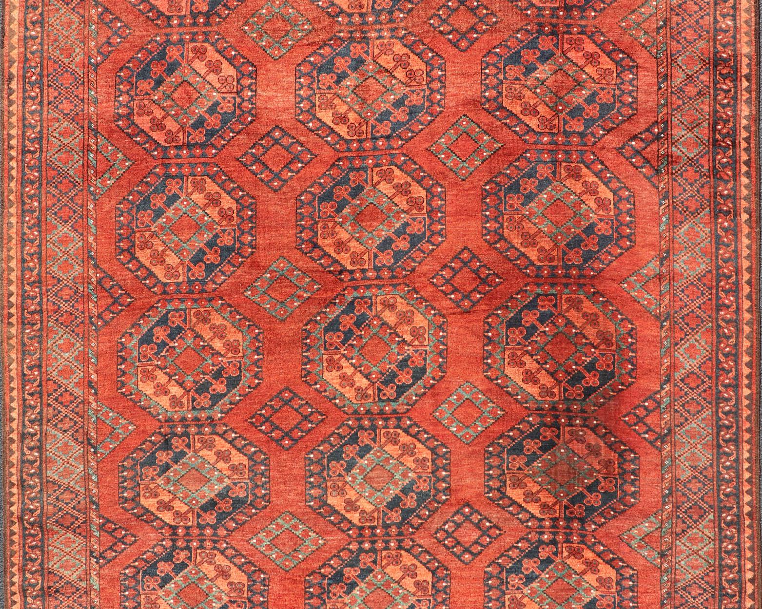 This Ersari rug has been hand-knotted in the finest wool. The rug features a repeating Gul design throughout the entirety of the piece, enclosed within a complementary, multi-tiered border, depicting small repeating motifs. The rug is rendered in