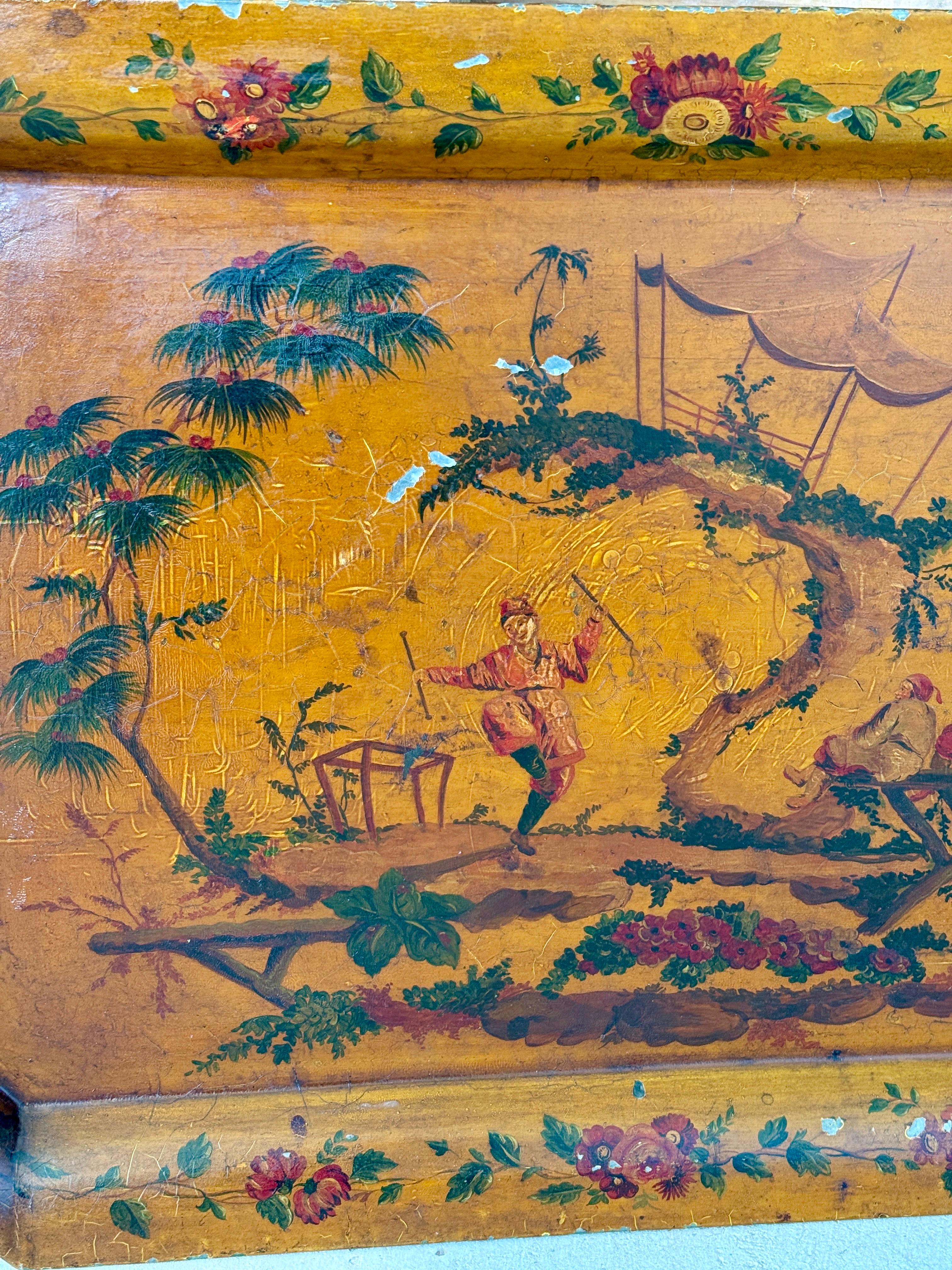 Exquisita bandeja de toletería de principios del siglo XX pintada a mano con una encantadora escena de Chinoiserie con figuras, una pagoda y exuberantes detalles florales sobre un cálido fondo dorado.
La forma octogonal festoneada está bordeada con