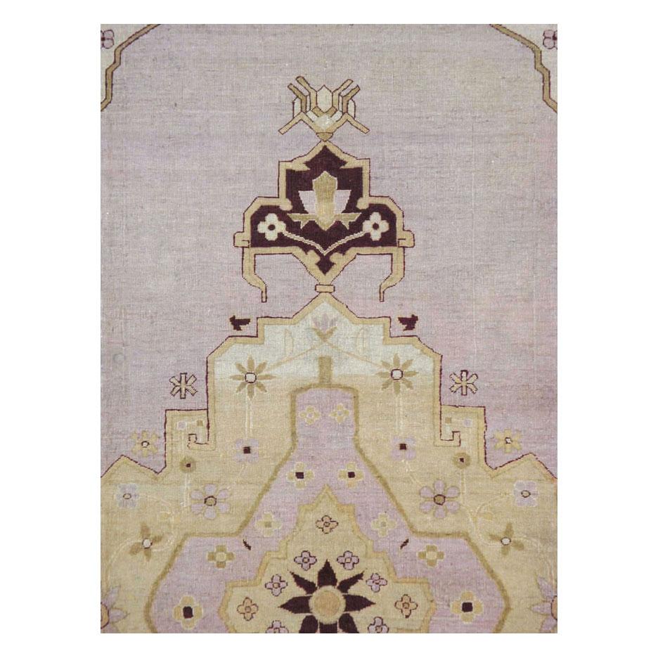 An antique Indian Agra room size area rug handmade during the early 20th century with a solid pale purple field, and a large scale medallion and border in beige. No clutter, just grand and masculine motifs in an elegant color palette.

Measures: