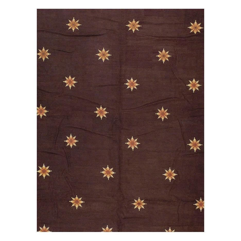 An antique French needlepoint large oversized carpet handmade during the early 20th century. Spaced small stars fill the burgundy field while scrolling three-dimensional oak leaves fill the morning glory border of this antique piece matched