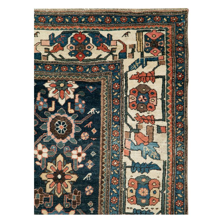 An antique Persian Bidjar accent rug handmade during the early 20th century in dark blue with an ivory border encompassed by overhead floral elements.

Measures: 5' 2