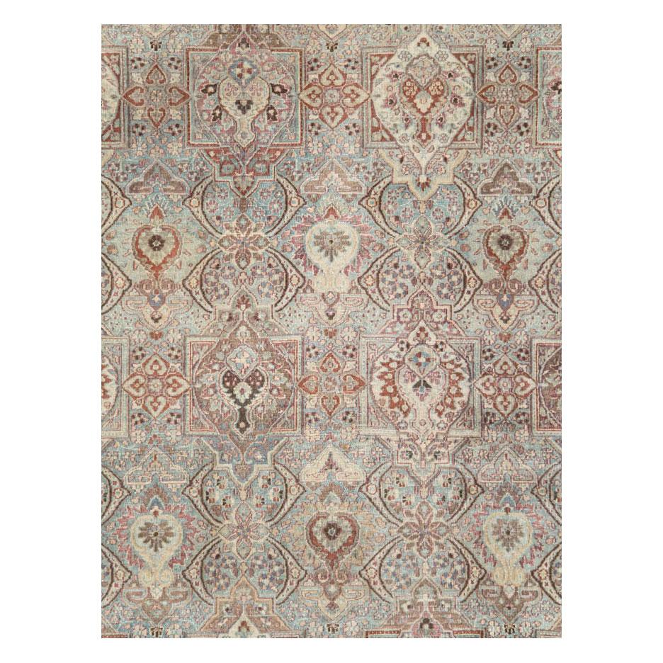 Un tapis persan antique de grande taille, de type Mashad, fait à la main au début du 20e siècle, avec un motif complexe sur toute la surface, dans une palette de couleurs douces de bleus clairs, de gris et de violets.

Mesures : 11' 2