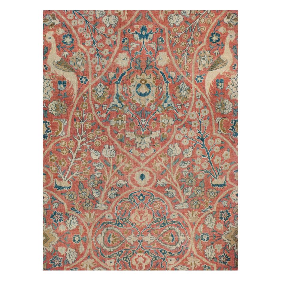 An antique Persian Tabriz large room size carpet handmade during the early 20th century. Floral sprouts decorate the field along with an arabesque pattern shaping a quatrefoil and spade-like design. Paired pheasant birds stand atop the floral