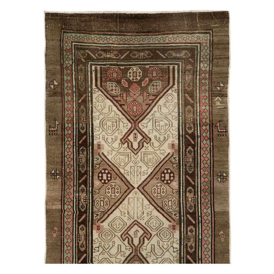 An antique Persian Serab rug in runner format handmade during the early 20th century in shades of brown and cream among other colors.

Measures: 3' 2
