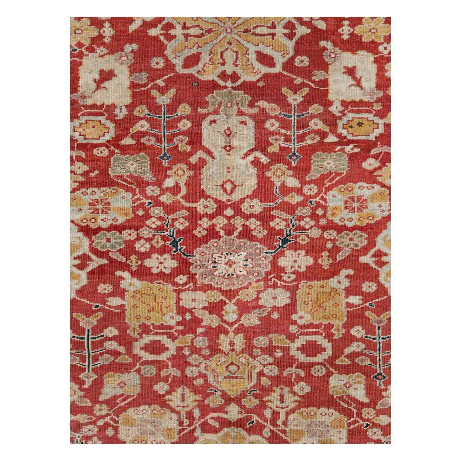 An antique Persian Sultanabad long and narrow rustic carpet in gallery format handmade during the early 20th century with a Classic all-over design enclosed by a 'turtle palmette' border all in traditional Persian jewel tones including red, dark