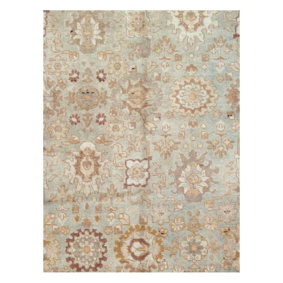 An antique Persian Tabriz accent rug handmade during the early 20th century with a muddled and light slate grey field with blue-green variations and a light burnt umber border. It is apparent that the city workshop of Tabriz took one from the books