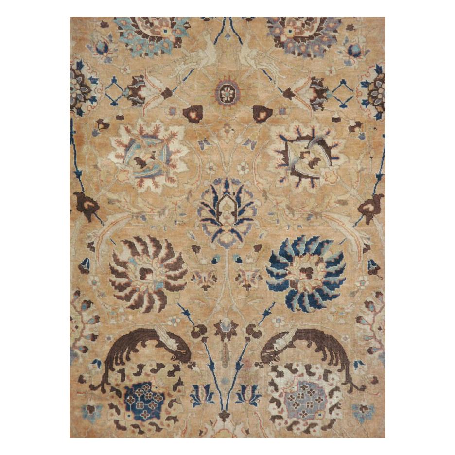 An antique Persian Tabriz room size carpet handmade during the early 20th century with a cream field and blue border.

Measures: 9' 2