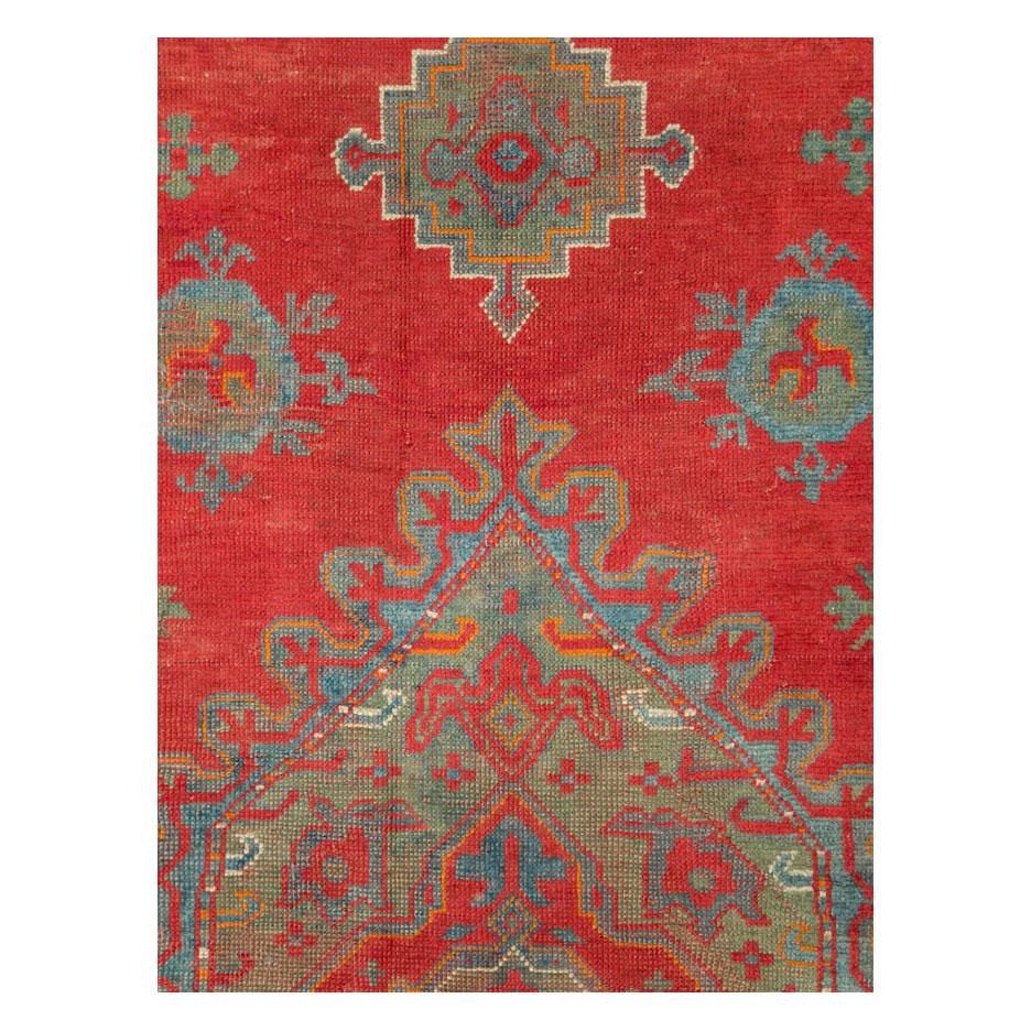 An antique Turkish Oushak rug in gallery format handmade during the early 20th century with a large medallion over a solid, rich red, field.

Measures: 6' 1