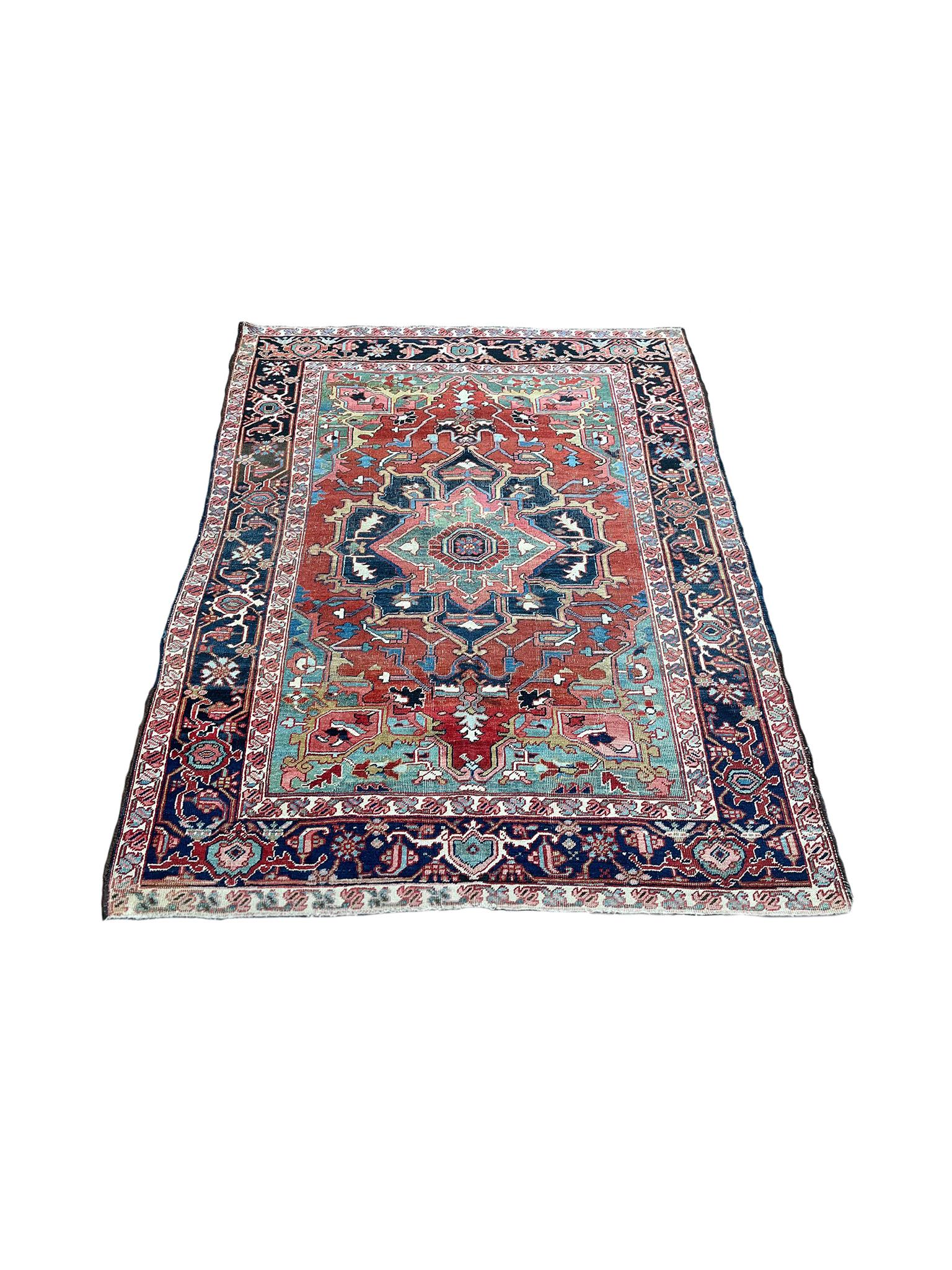Woven in the Early 20th Century, this Persian Heriz rug is designed with a classic central medallion framed by a series of densely patterned borders. Floral and vine motifs compose the patterns in a brilliant palette of blues, reds, greens, and