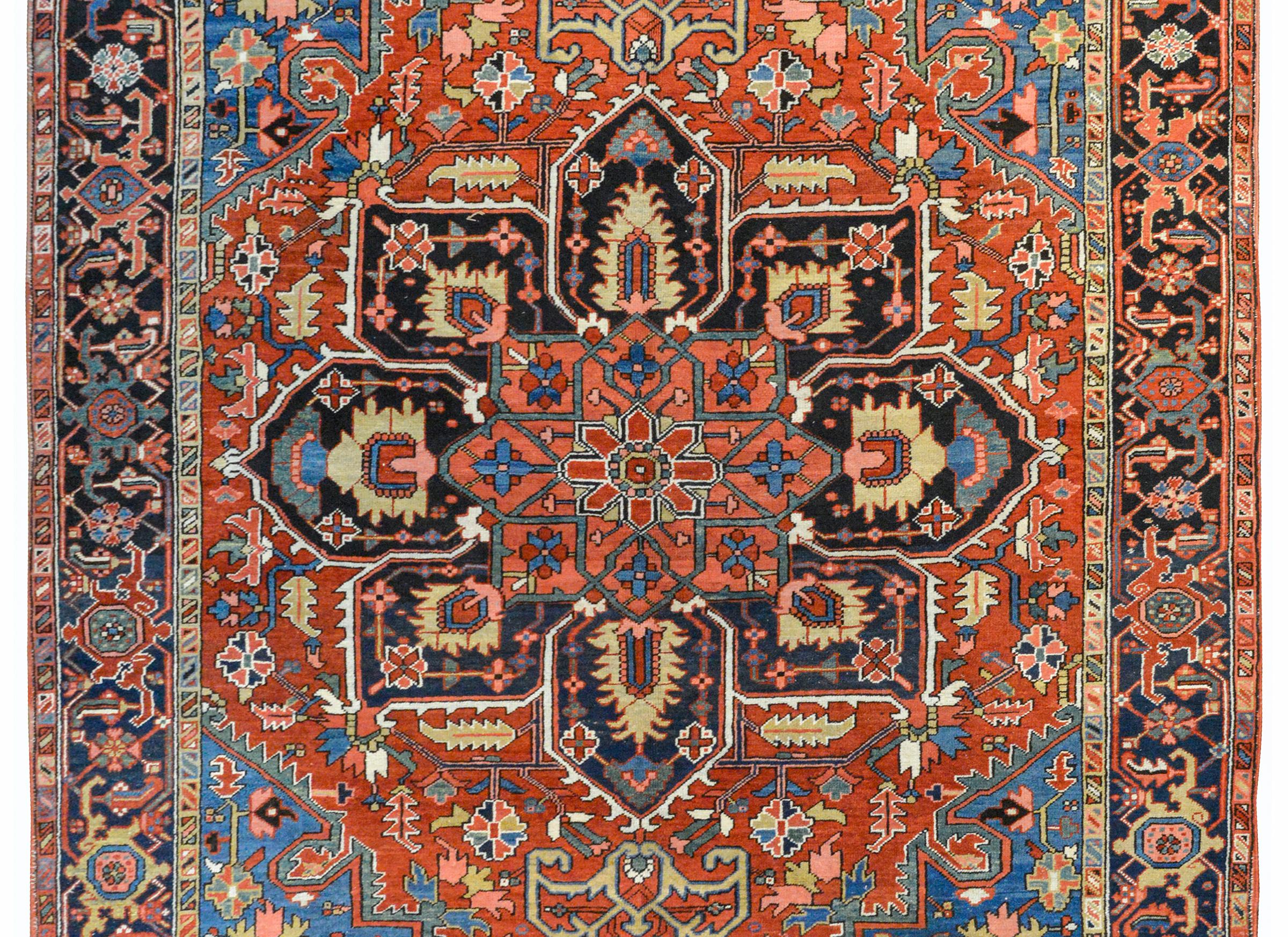 A wonderful early 20th century Persian Heriz rug with a rather large central floral medallion woven with more flowers and vines and woven in crimson, salmon, green, gold, indigo and black wool against a field of even more flowers and leaves, and