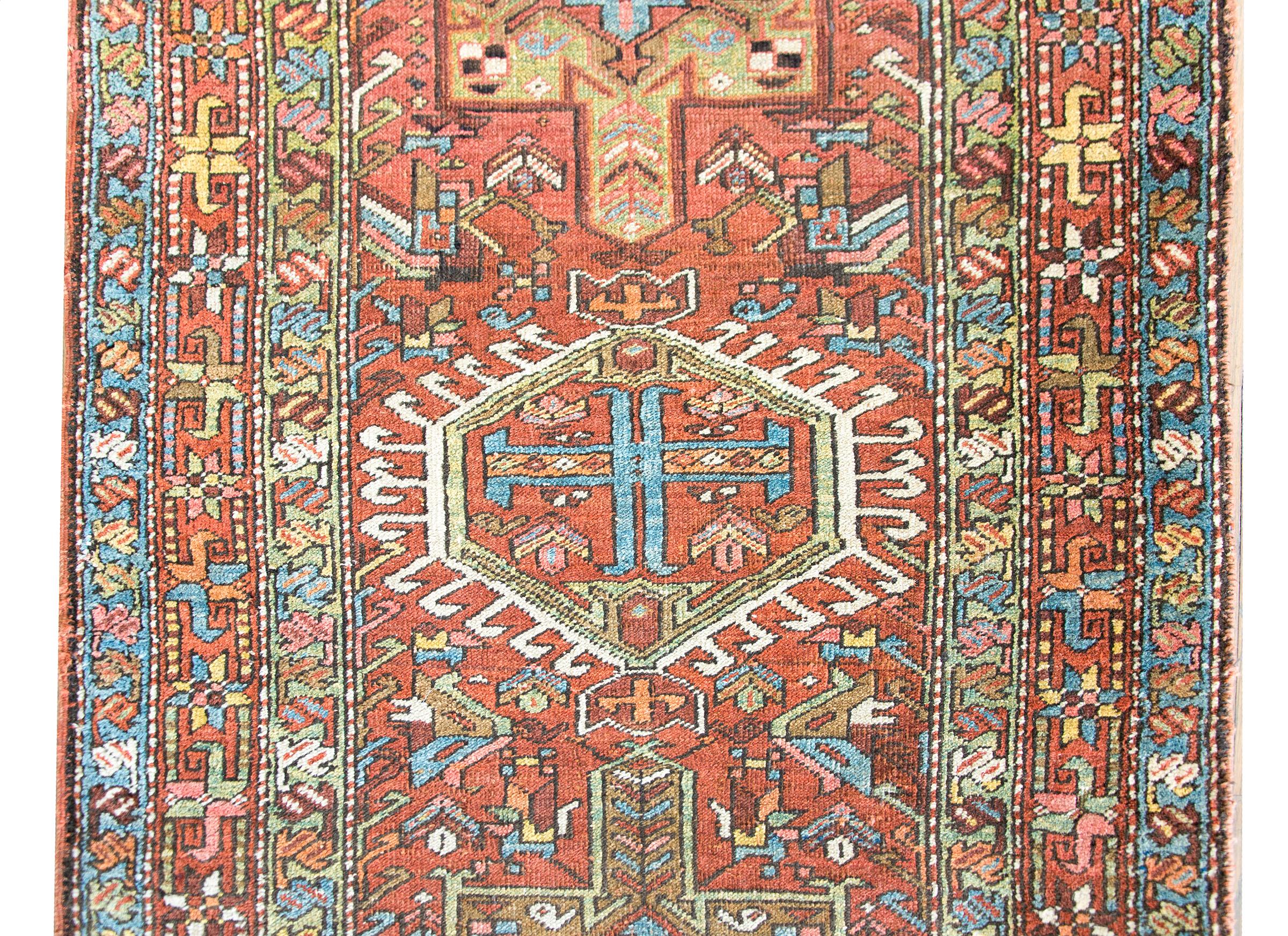 A stunning early 20th century Persian hertz runner with myriad stylized floral medallions woven in pinks, indigos, whites, oranges, and crimsons, surrounded by a fantastic complex floral partnered stripe borders.