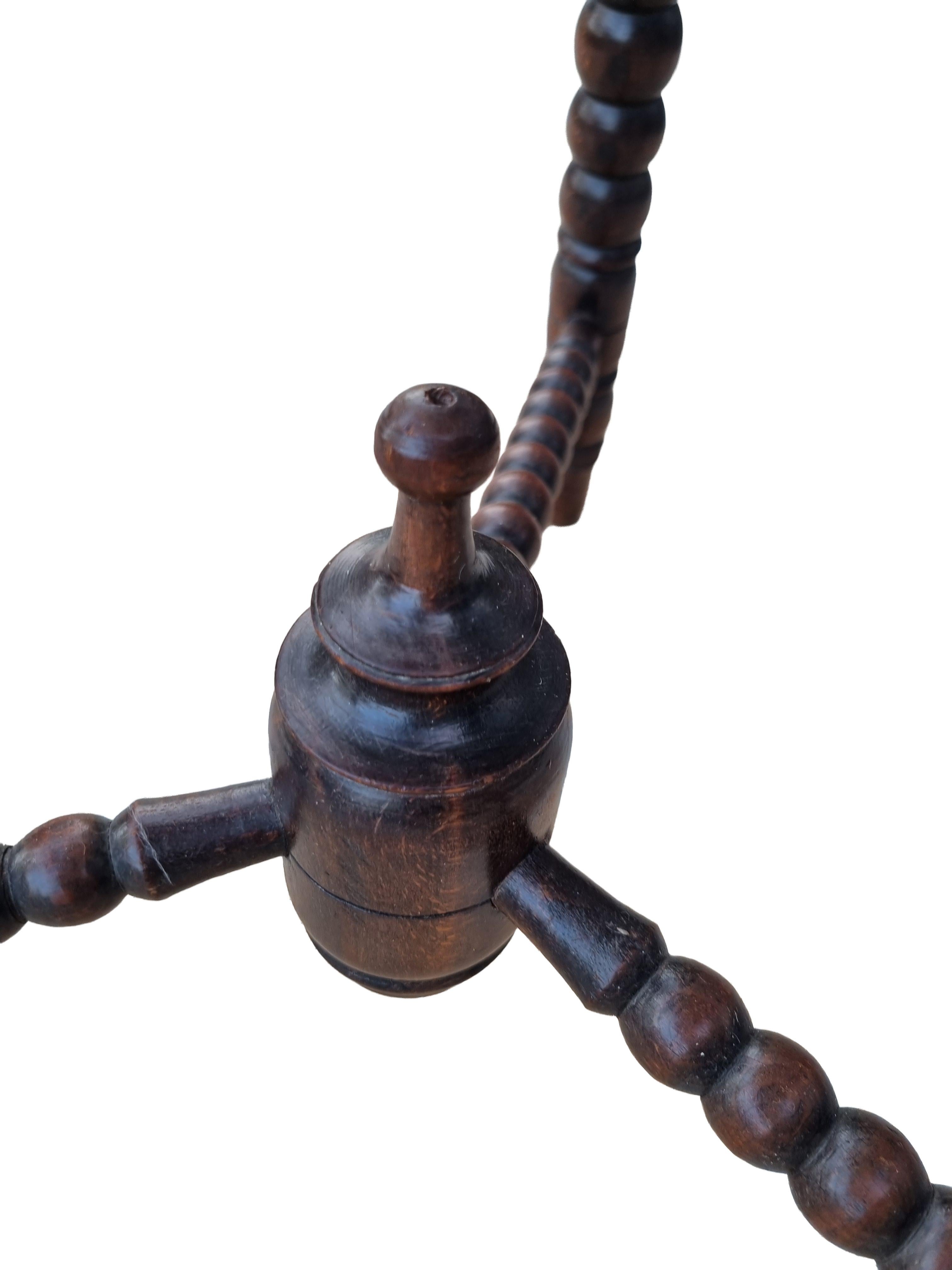 Charming hexagonal side table in solid oak, raised on three bobbin-turned (spool-turned) legs joined by a triangular stretcher that meets in a turned finial hub. The top shows a hand-carved beaded/gadrooned border and a warm, original patina with