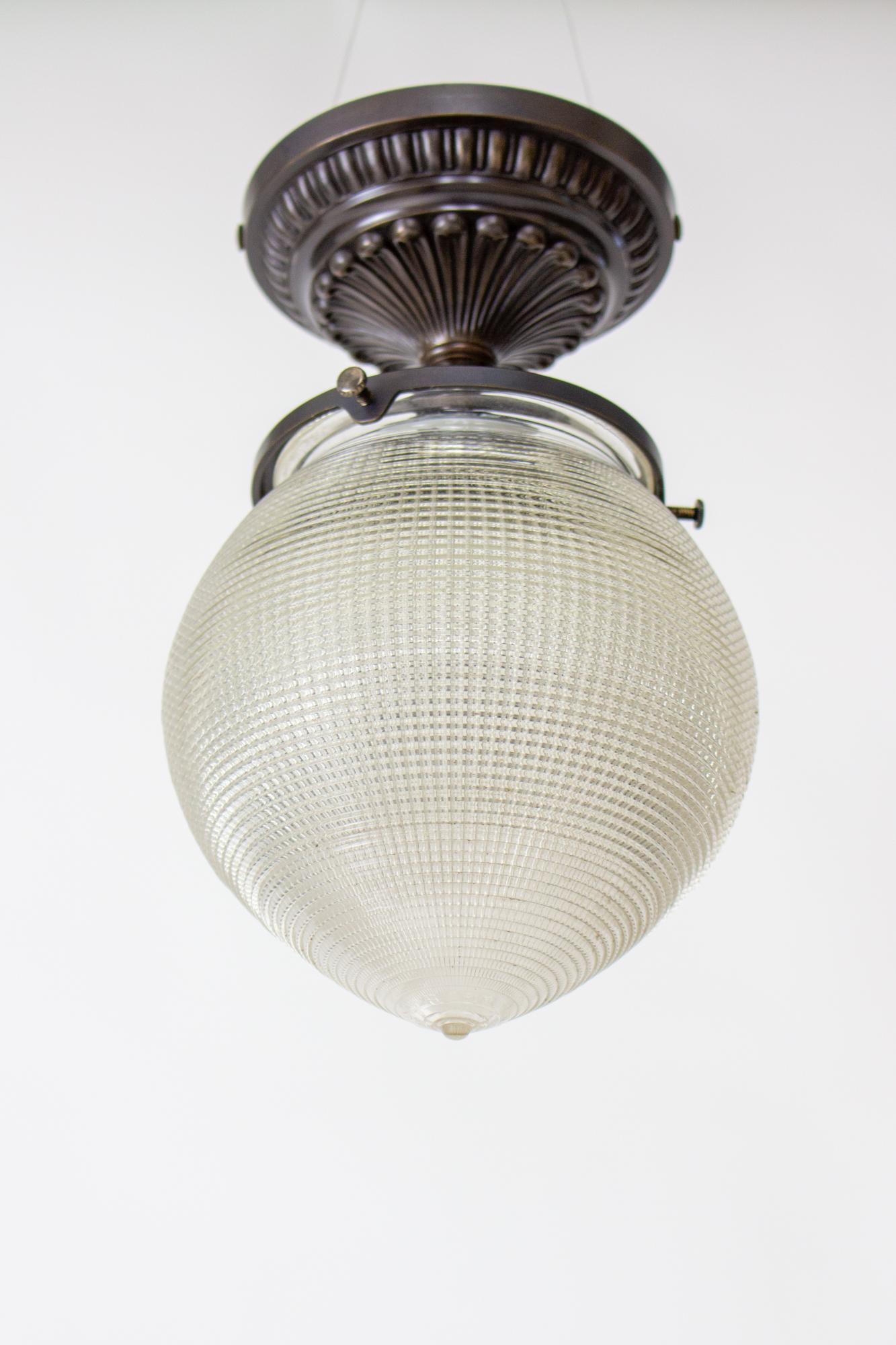Early 20th century Holophane prismatic flush mount fixture. Signed Holophane prismatic pointed glass shade. Darkened brass fixture with decorative cast canopy with a 4 ¾” diameter. Porcelain socket, can use up to 150 watts. Fixture is custom and in