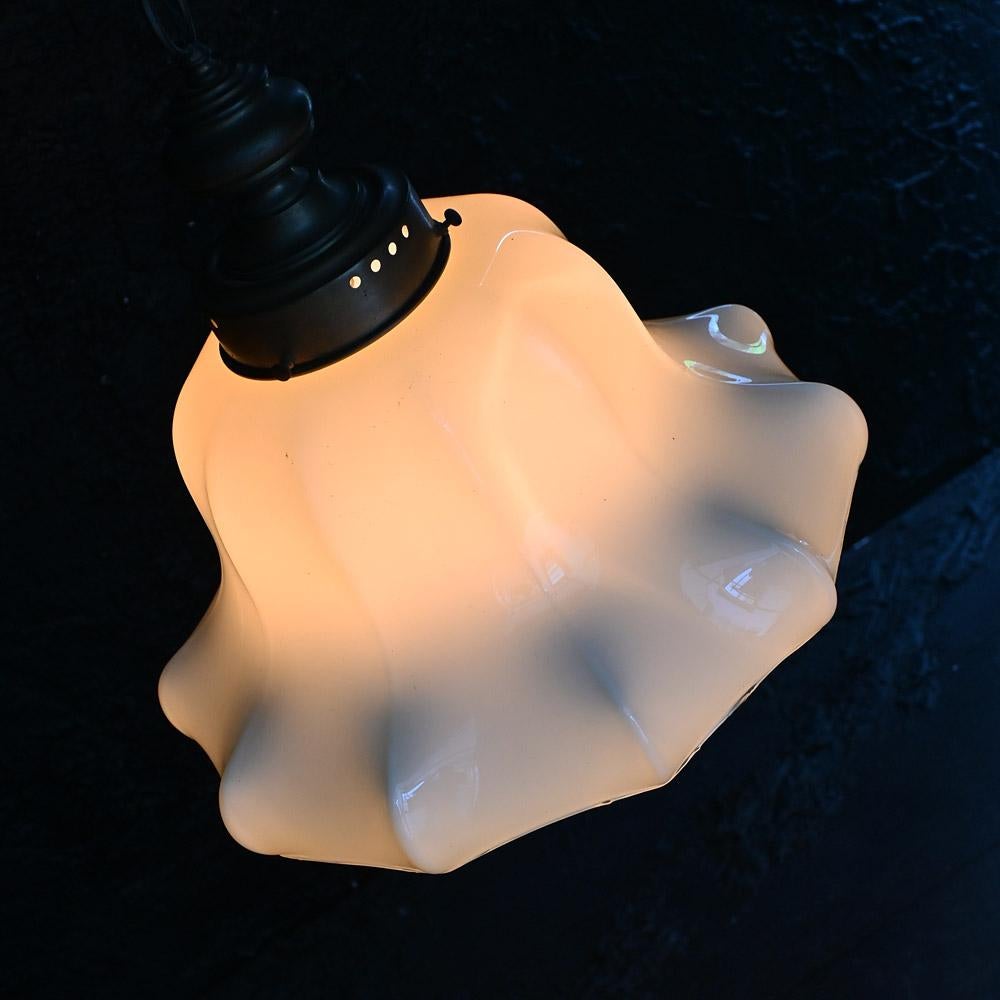 Early 20th century huge opaline glass light shade

A large untouched example of an early 20th century opaline glass light shade. With a warm glow across the glass which is shaped in the style of an open flower. With its original brass gallery,