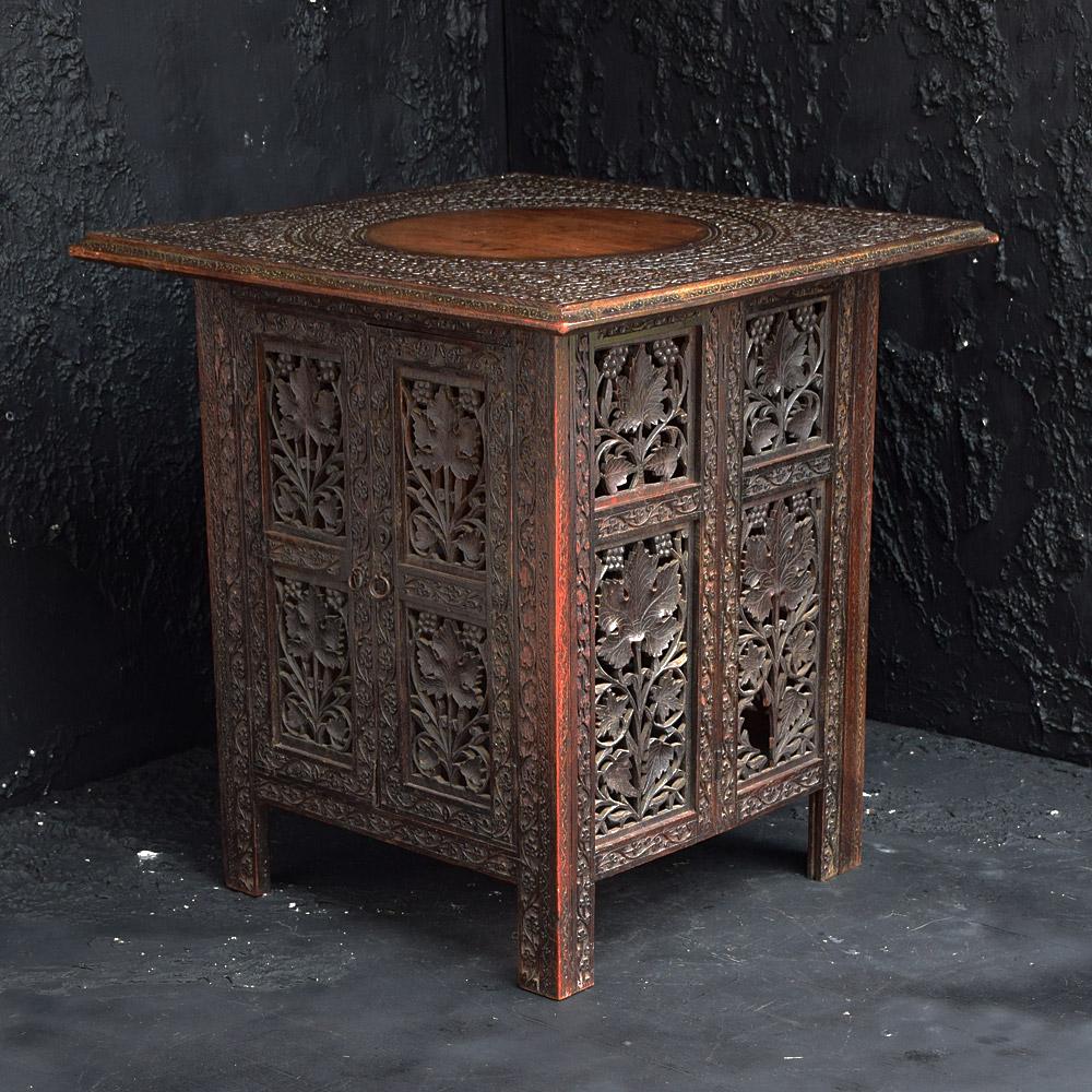 Early 20th century Indian carved table 

A highly decorative hand carved early 20th century North Indian side table. This piece of furniture has a hidden cupboard underneath. The table folds flat for easy storage and was referred to as an