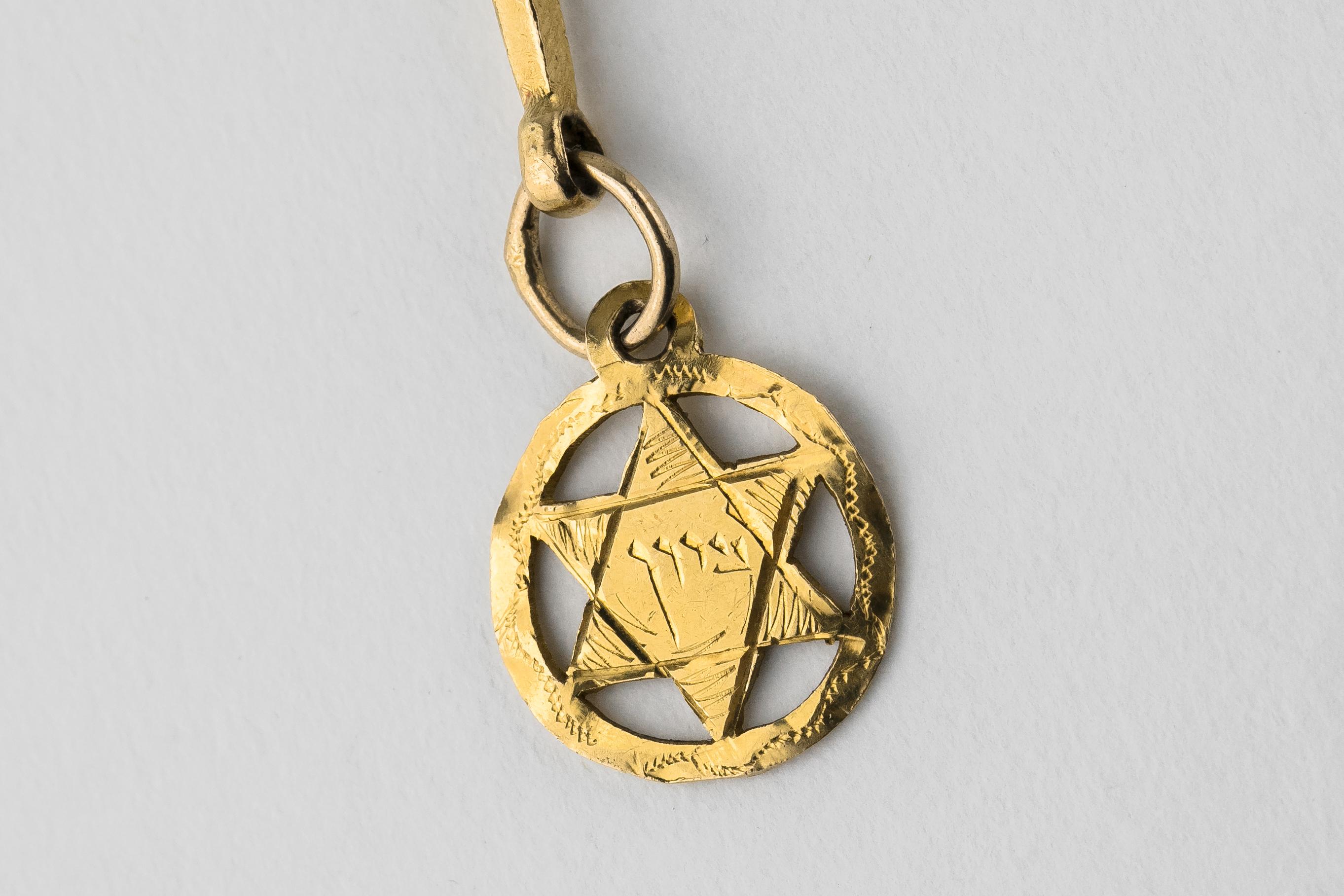 Handmade gold Torah pointer (Yad), India, circa 1900.
The flat part is hammered and engraved in Hebrew: Rivka M. and Avigael A. The shaft is twisted.
An open work gold medallion with Star of David engraved with the Hebrew word Zion is hanging from
