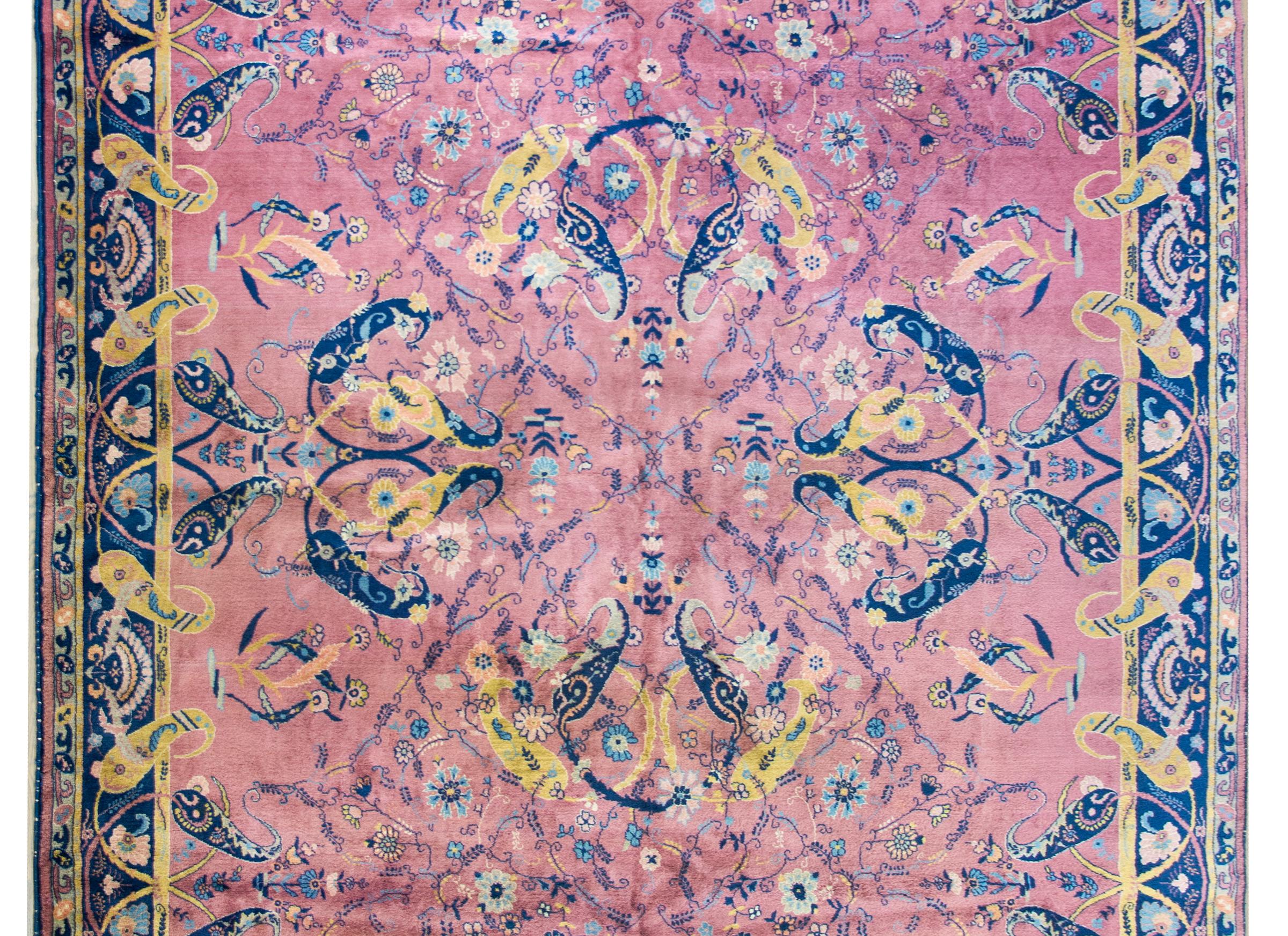 A beautiful early 20th century Indian Lahore rug with a large central medallion composed with swirling paisleys woven in indigo and gold, and living amidst a field of flowers, and all set against a pink background. The border is sensational with
