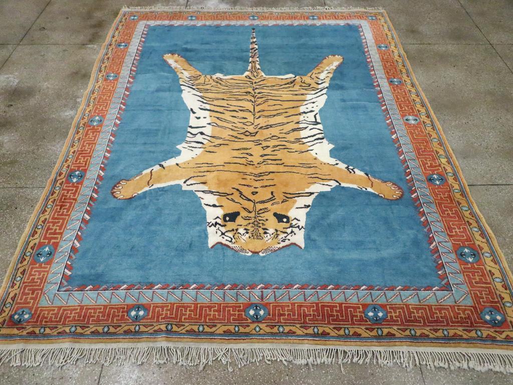 Una pila di nodi asimmetrici su una base di cotone. Questa insolita creazione in cotone di dimensioni rom sfoggia una pelle di tigre scuoiata nei colori ecrù e ocra su un campo aperto blu abraso. Bordo principale color ruggine con sezioni di tasti a