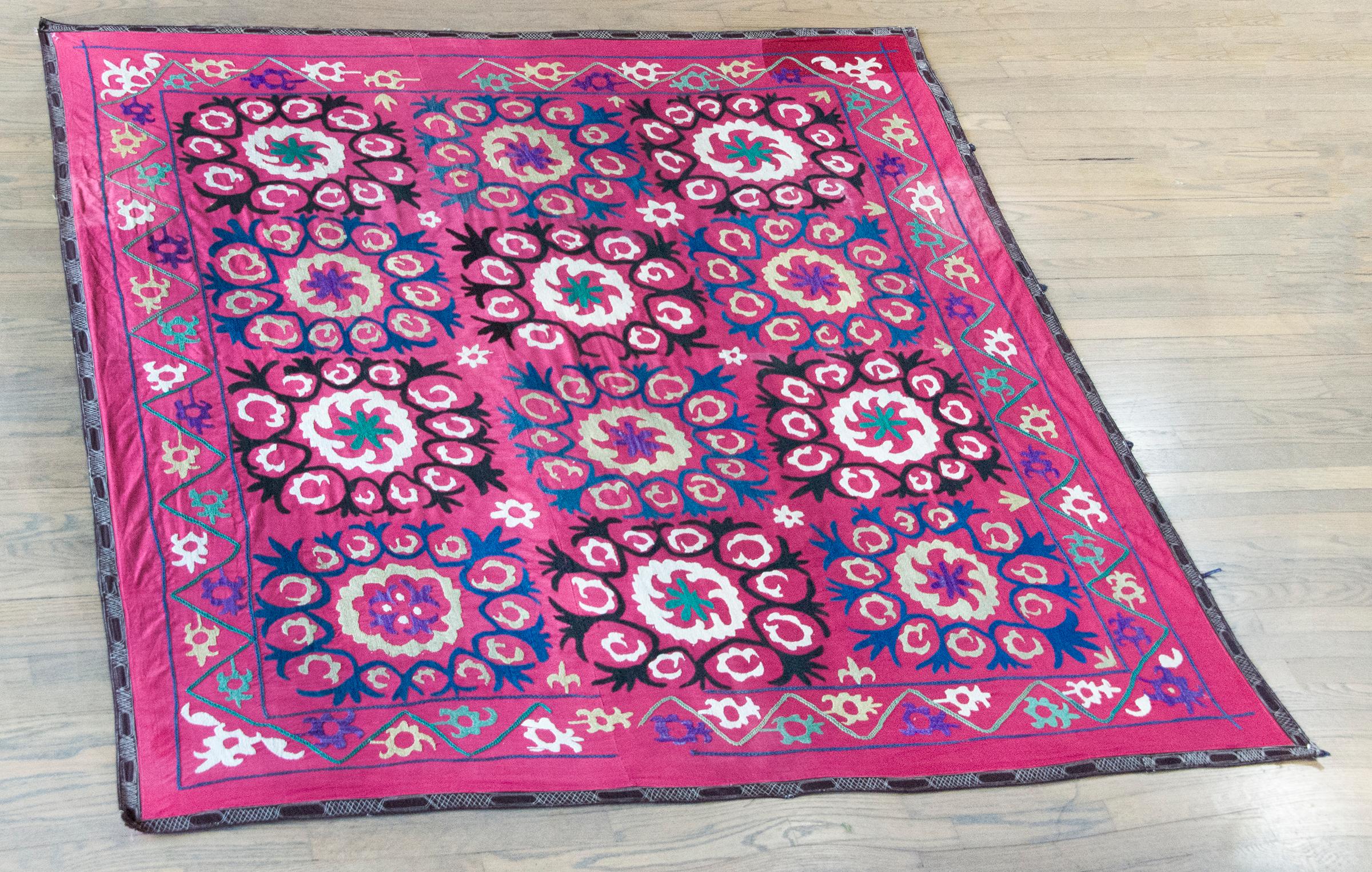 This vibrant vintage Indian hand-embroidered textile draws inspiration from Persian Suzanis, reinterpreted through a distinctly South Asian lens. A grid of large, bold floral medallions fills the field in rhythmic precision, each flower bursting